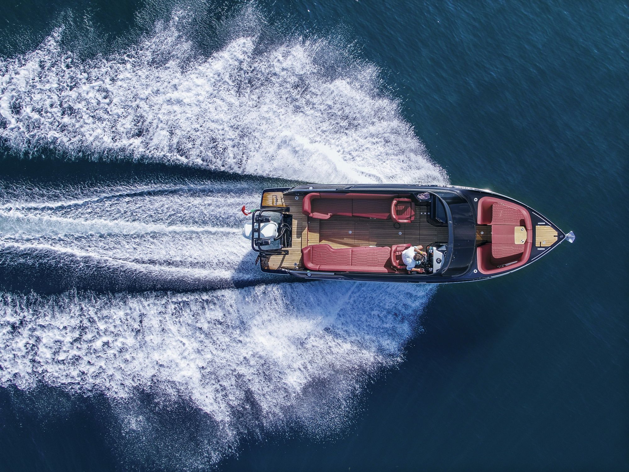 Aerial view of the Cranchi E26 Rider underway - the deck layout with red sofas is visible.