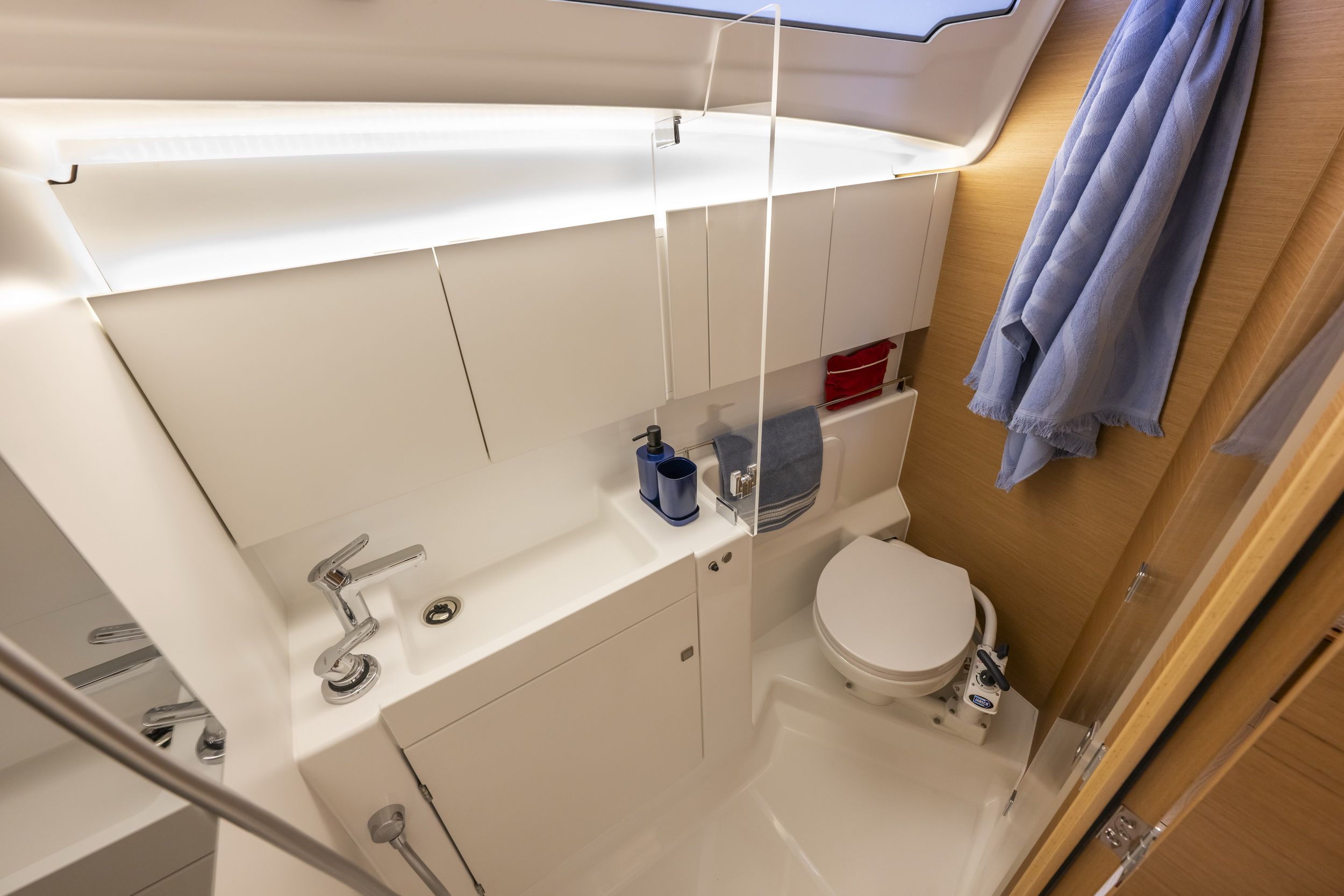 Wnętrze łazienki na jachcie Jeanneau Sun Odyssey 415, z umywalką, toaletą i wydzielonym prysznicem.