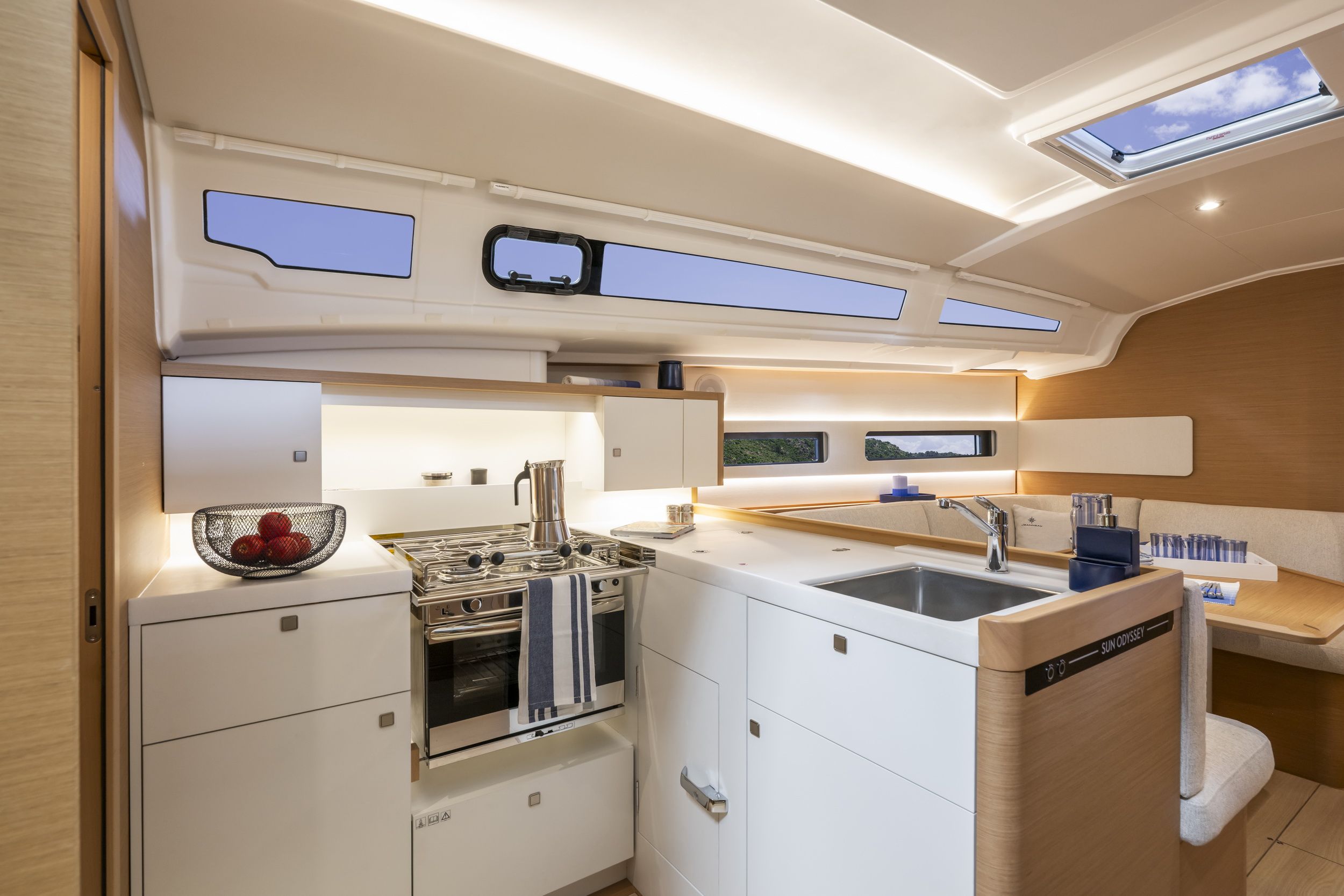 Innenraum der Segelyacht Jeanneau Sun Odyssey 415 mit Blick auf die moderne Kombüse mit Kocher, Backofen und Spüle sowie einem Teil des Salons.