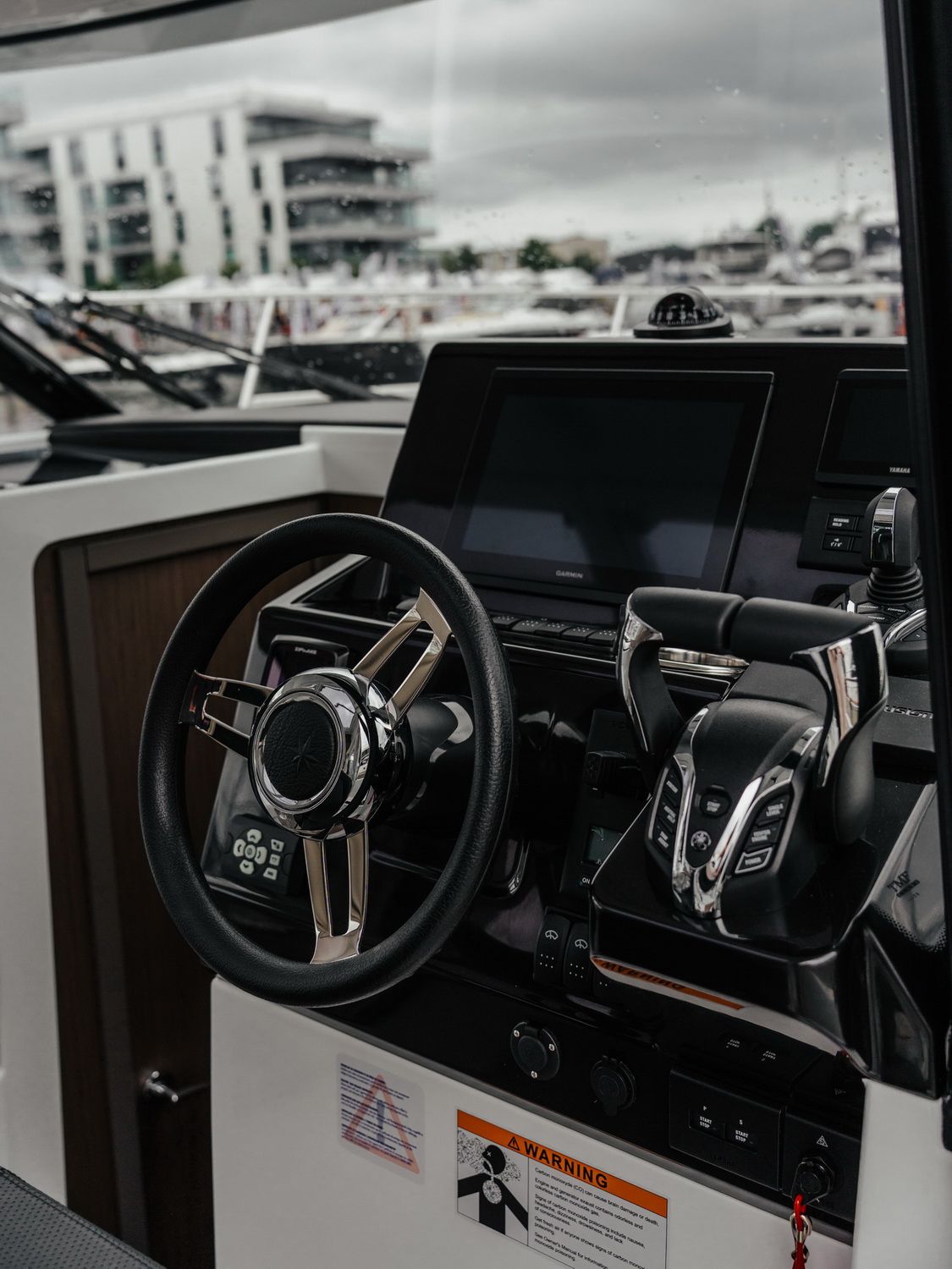 Widok na stanowisko sternika z kierownicą, wyświetlaczami Garmin i Yamaha oraz manetkami silnika na jachcie Jeanneau Merry Fisher 895.