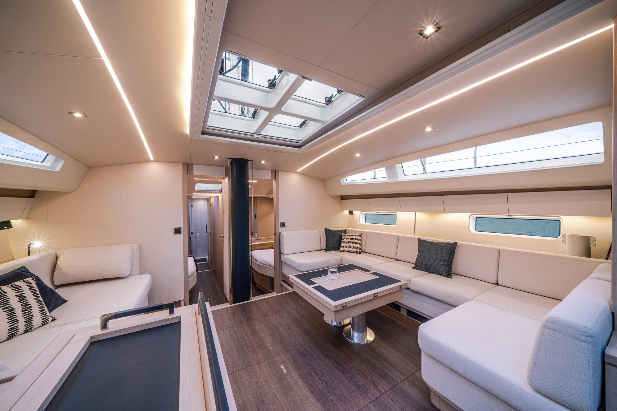 Geräumiger Salon der Jeanneau Yachts 65 mit großem U-förmigem Sofa, Tisch und Lexan-Fenstern.