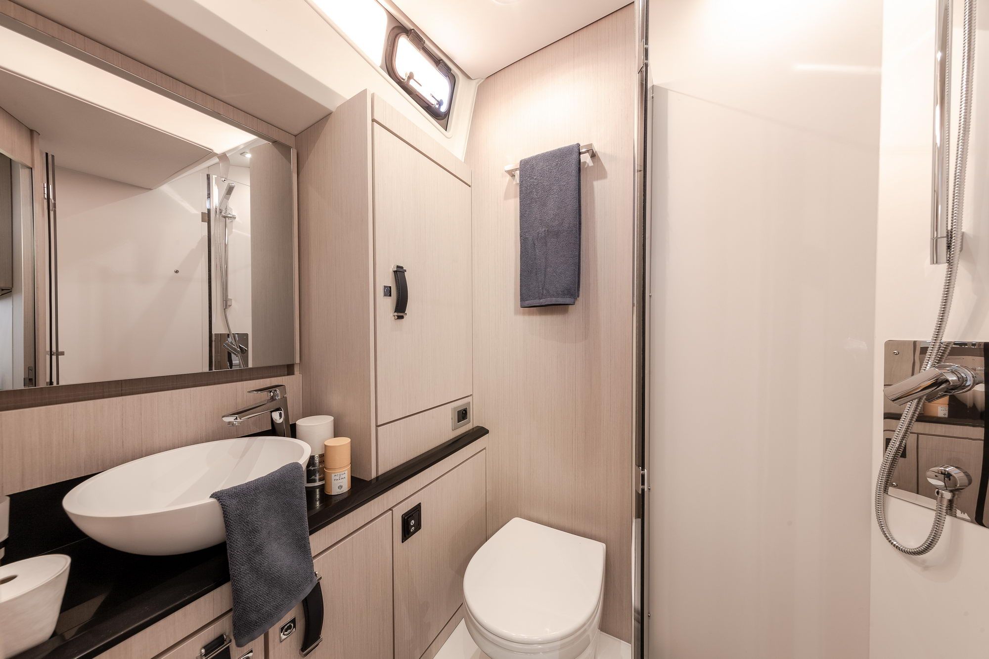 Modern bathroom on the Jeanneau Yachts 60 with a washbasin, toilet, shower and cabinets. Light finish.