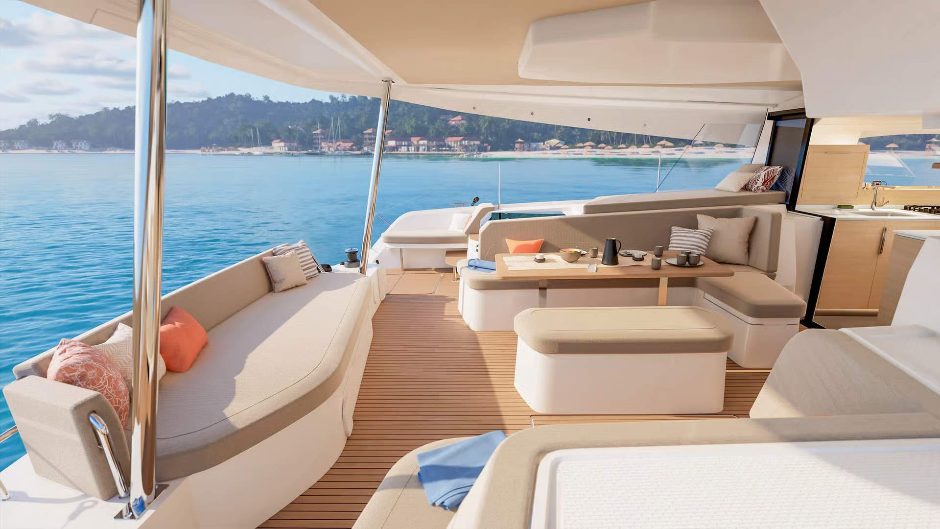 Fountaine Pajot FP48, przestronny kokpit rufowy z miejscami do siedzenia i stołem, widok na morze i wybrzeże.