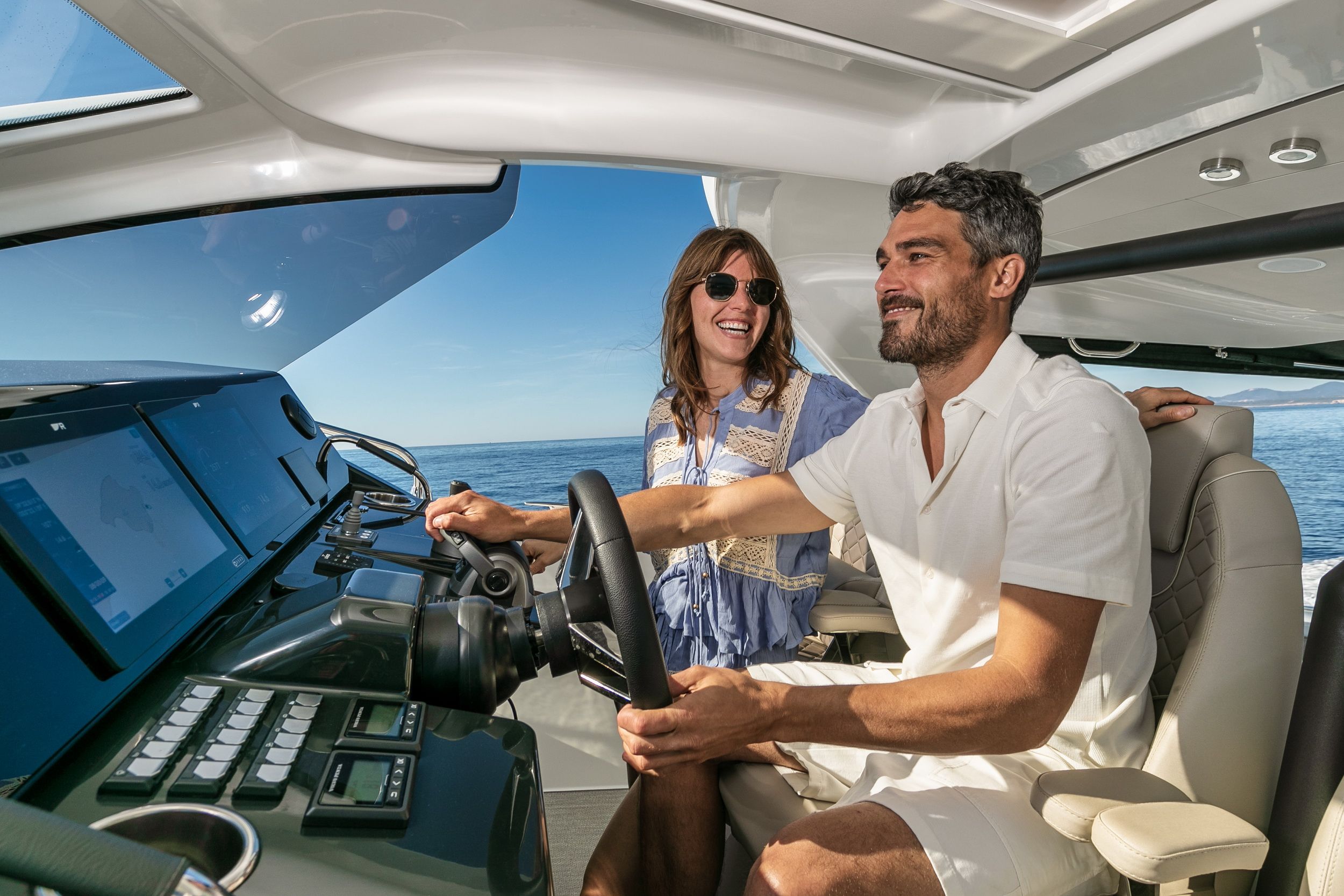 A man steering the Jeanneau DB/37 IB with a woman beside him, view of the cockpit and electronics.
