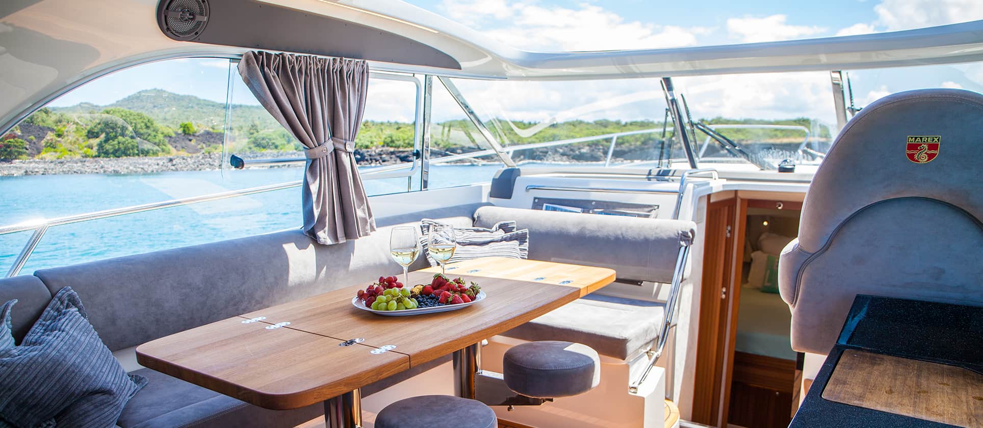 Innenraum des Cockpits der Marex 375 mit Holztisch, Sofa und Meerblick.
