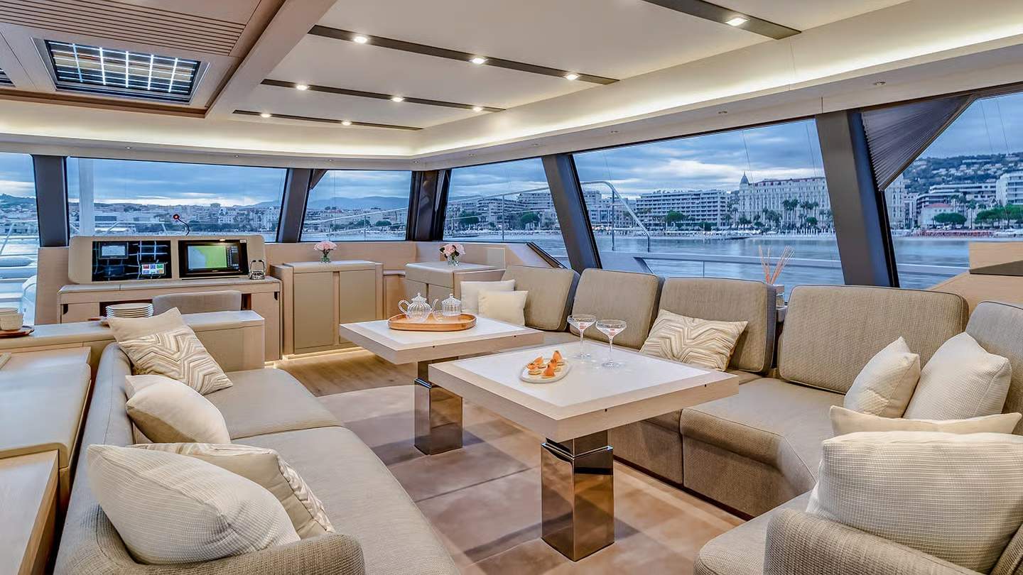 Luksusowy salon główny katamaranu Fountaine Pajot Thíra 80 z wygodnymi sofami, stolikami i widokiem na miasto.