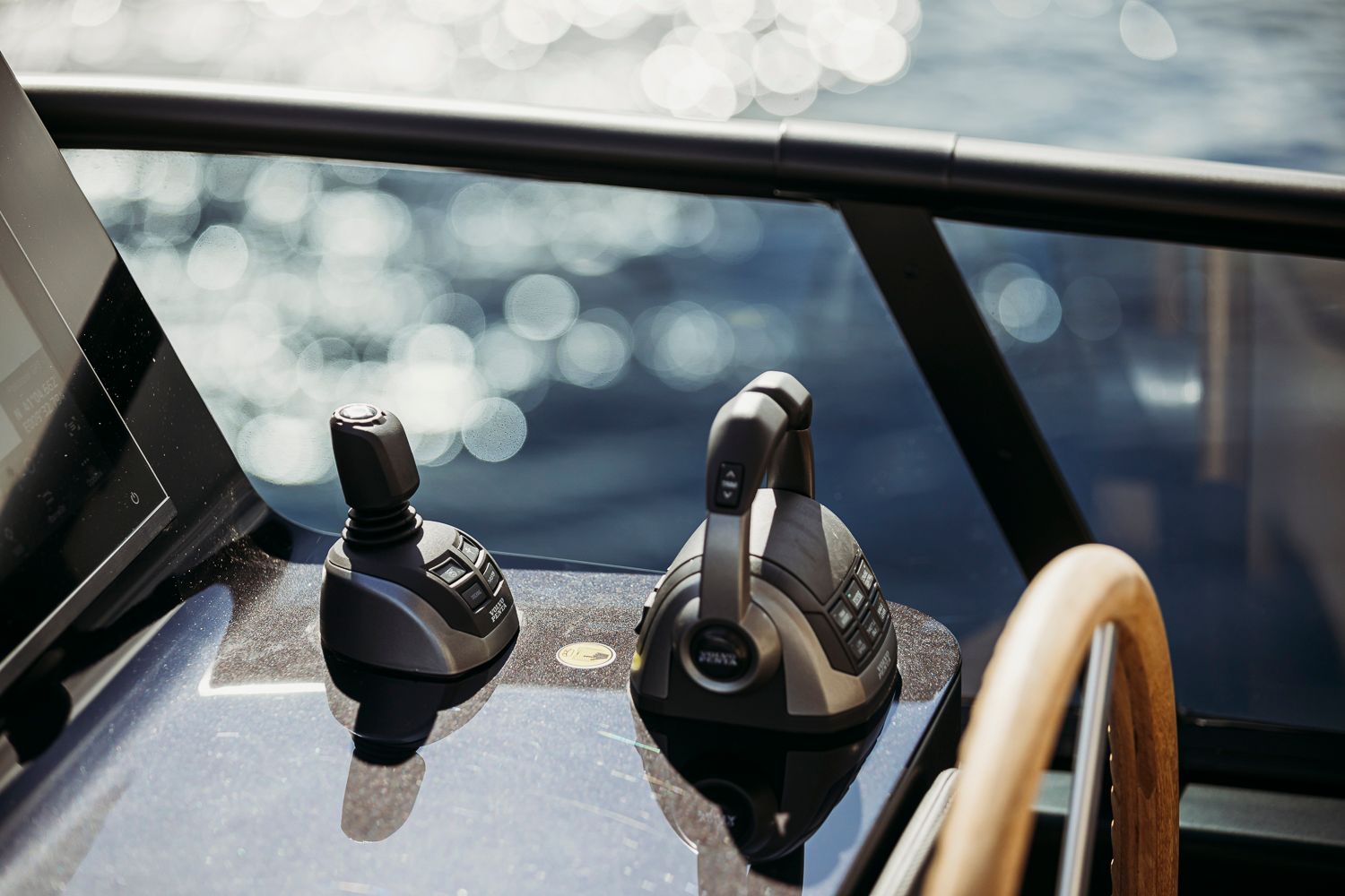 Bedienpanel der Cranchi Sessantadue 62 mit Joystick, Gashebeln und Ausschnitt eines Navigationsdisplays, im Hintergrund Wasser.