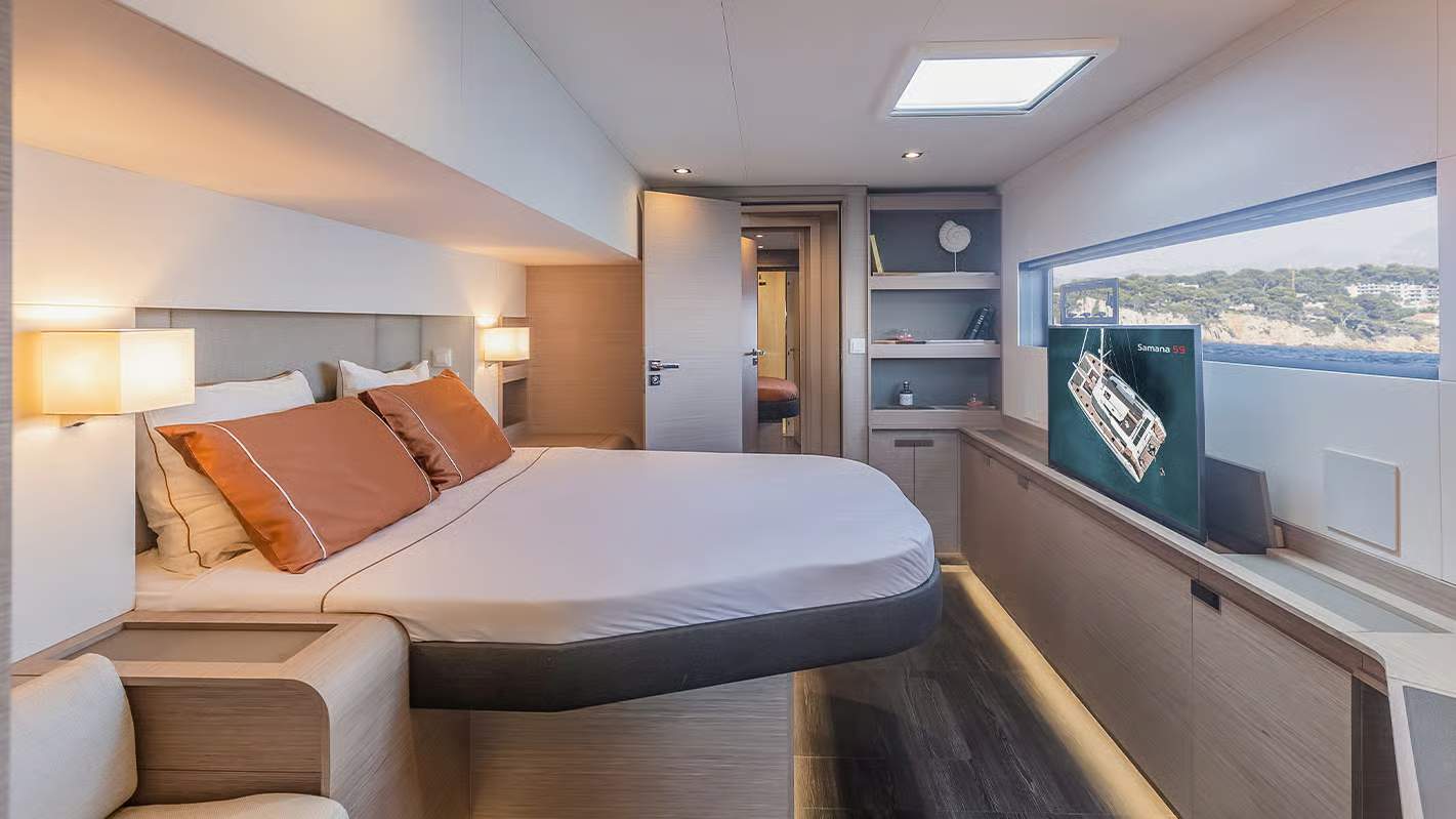 Luksusowa sypialnia armatorska na katamaranie Fountaine Pajot Samana 59 z dużym łóżkiem, oknem i telewizorem.