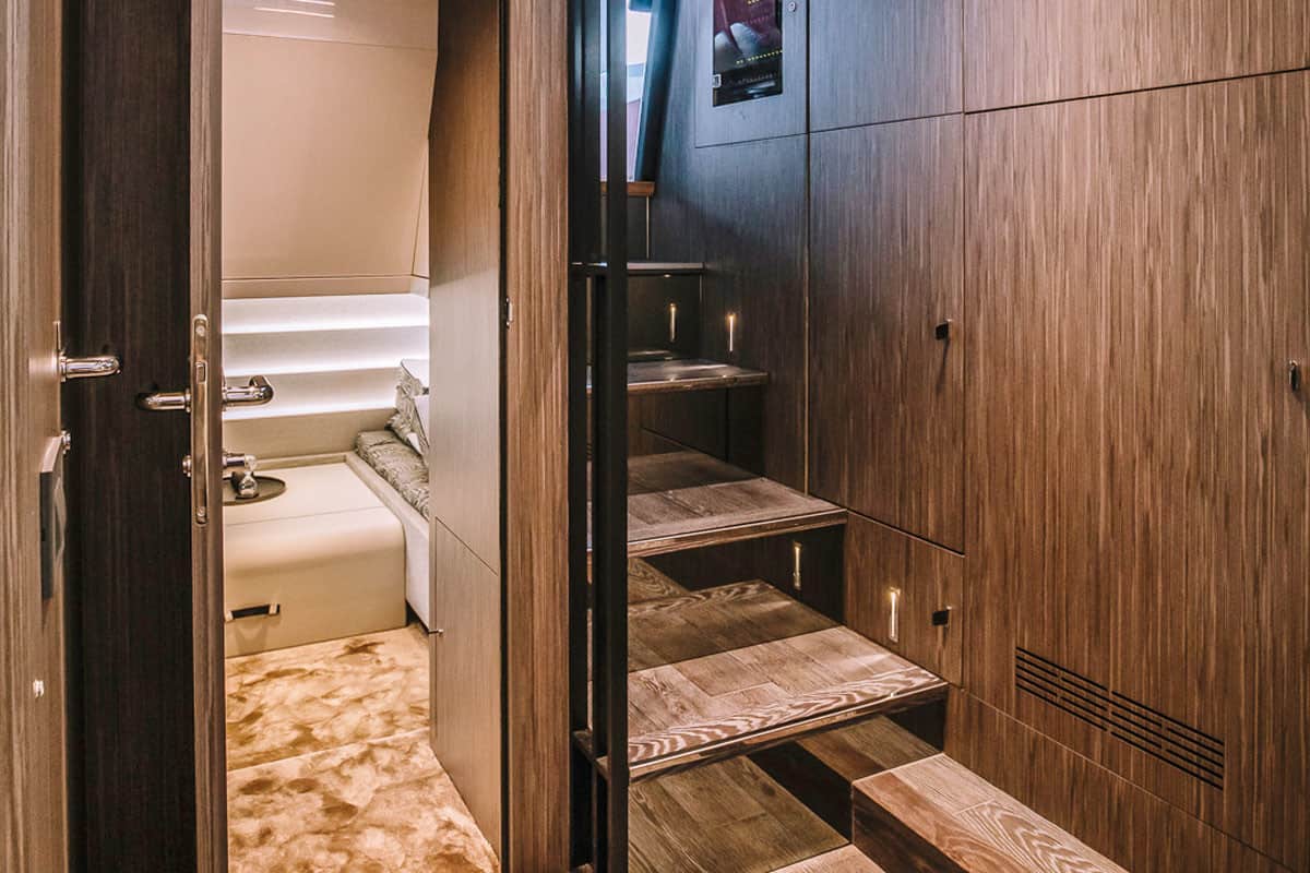 Beleuchtete Holztreppe, die zu einer Schlafkabine auf der luxuriösen Cranchi A46 Luxury Tender führt.