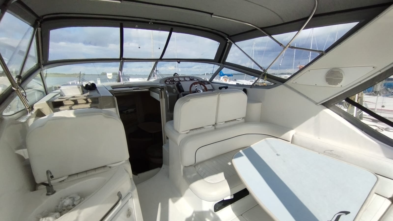 Widok na przestronny kokpit jachtu motorowego Bayliner 3055 z miejscami siedzącymi, stołem i stanowiskiem sternika.