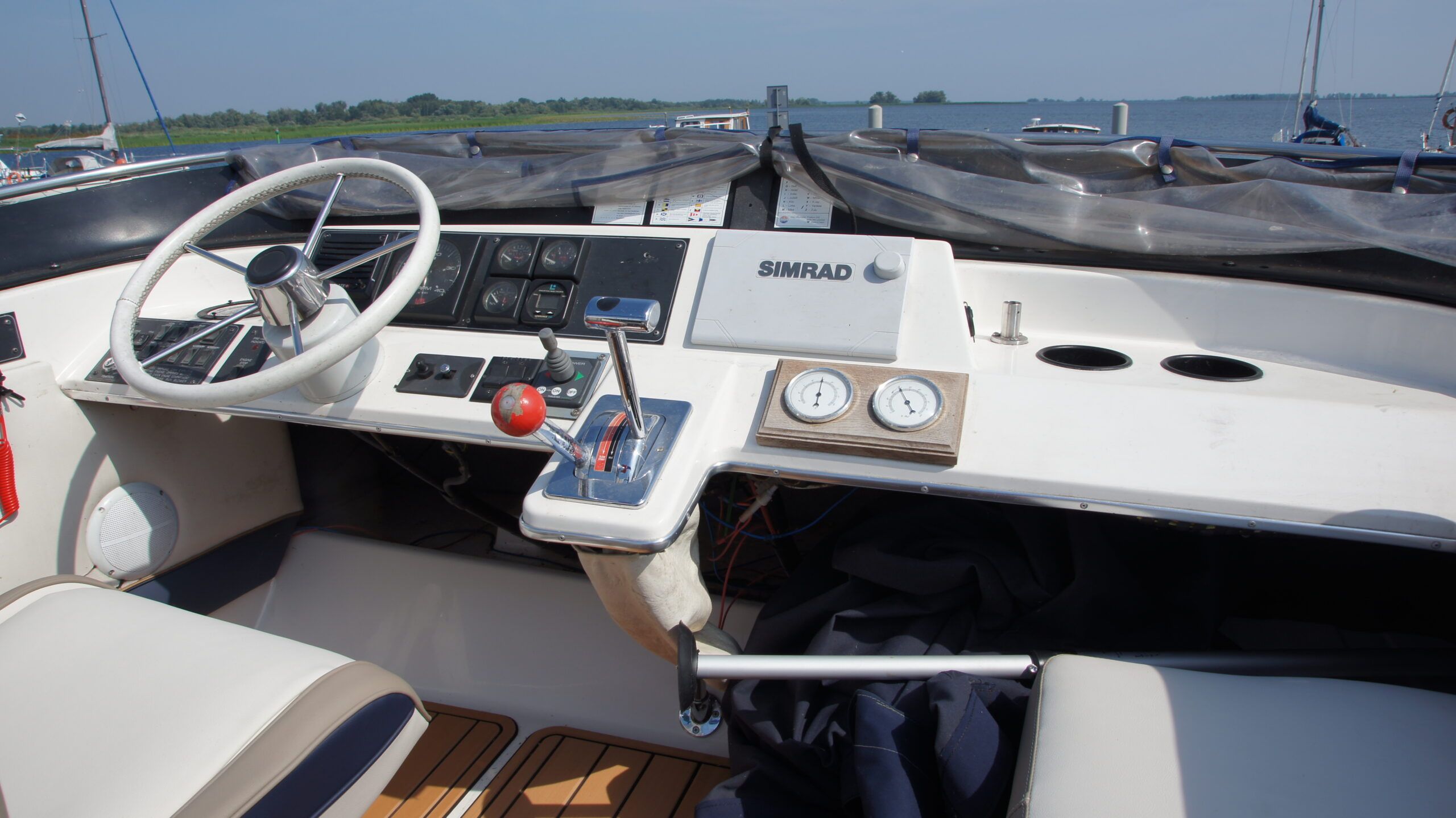 Widok na stanowisko sterowe na pokładzie Flybridge jachtu Bayliner 2858 Classic Fly, z kierownicą, manetką i ploterem Simrad.
