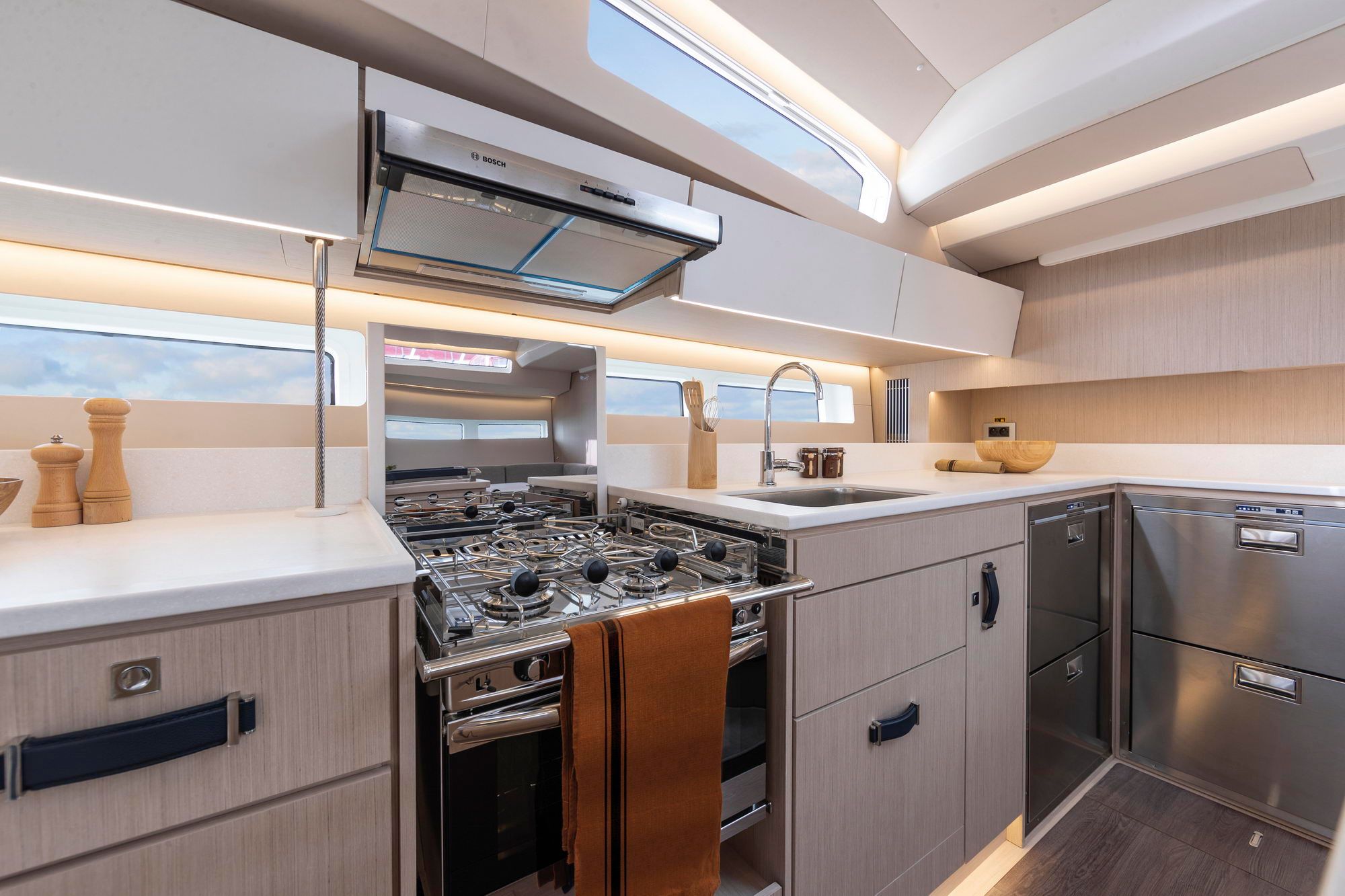 Innenraum der Kombüse der Jeanneau Yachts 55. Sichtbar sind Gasherd mit Backofen, Spüle, Schubladenkühlschrank und Dunstabzugshaube.