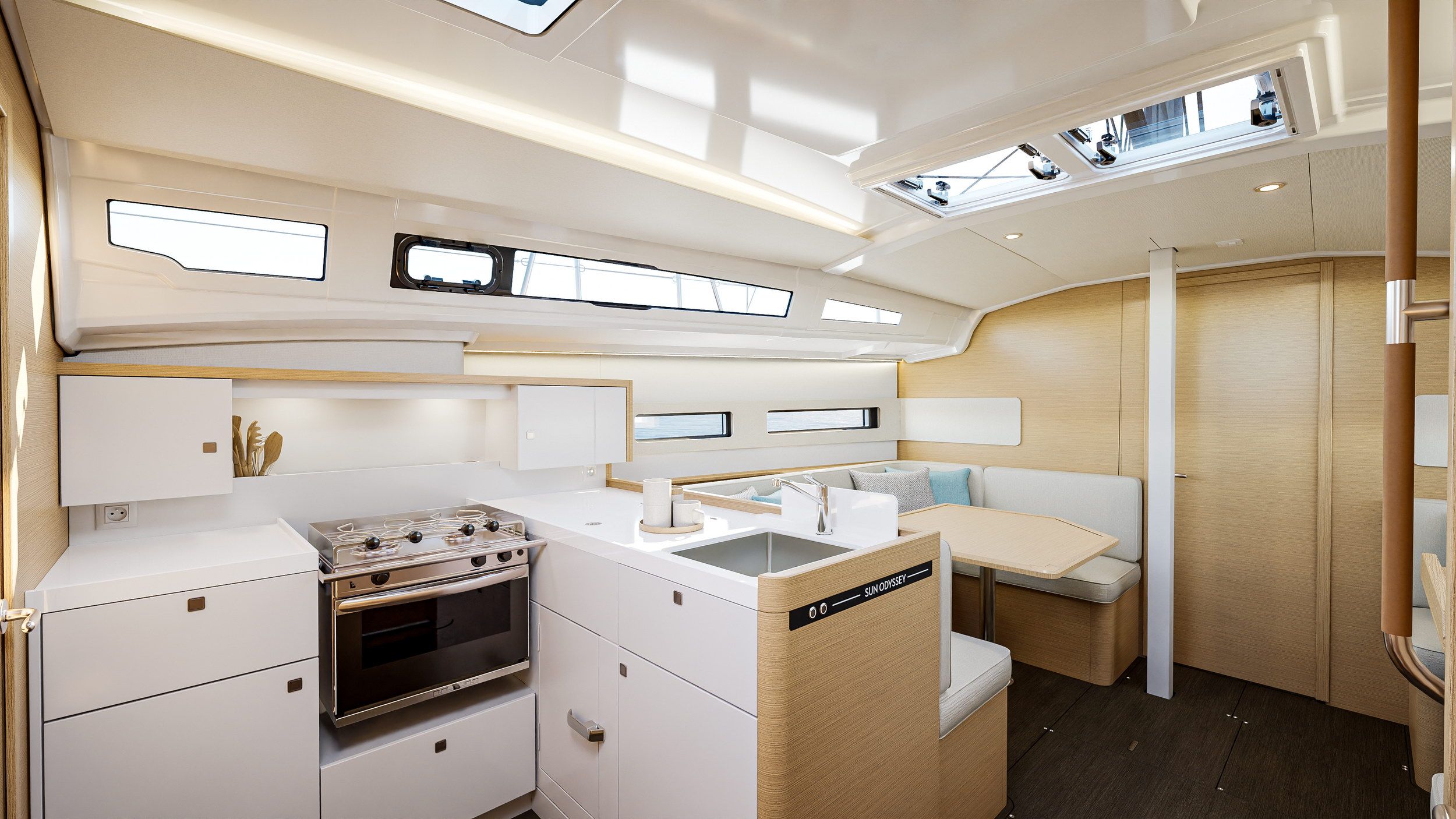 Innenraum der Jeanneau Sun Odyssey 415: moderne Kombüse mit Kocher und Spüle, daneben der Salon mit Sofa und Tisch.