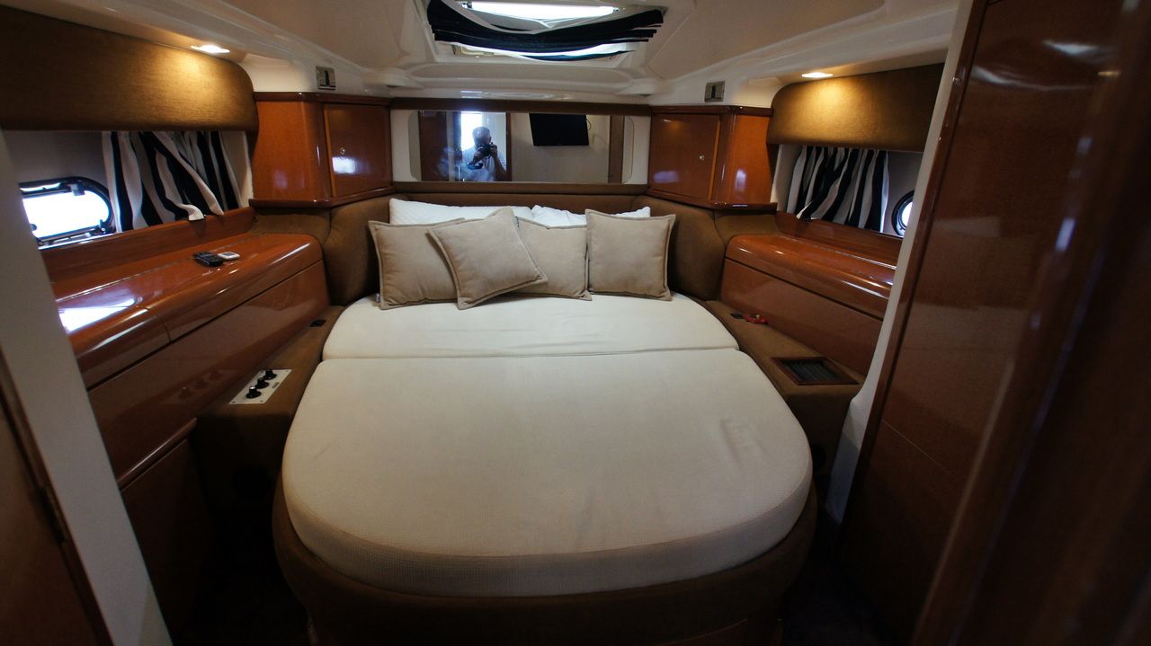 Spacious sleeping cabin on the Sealine F44 with a large bed, wooden finishes and windows.