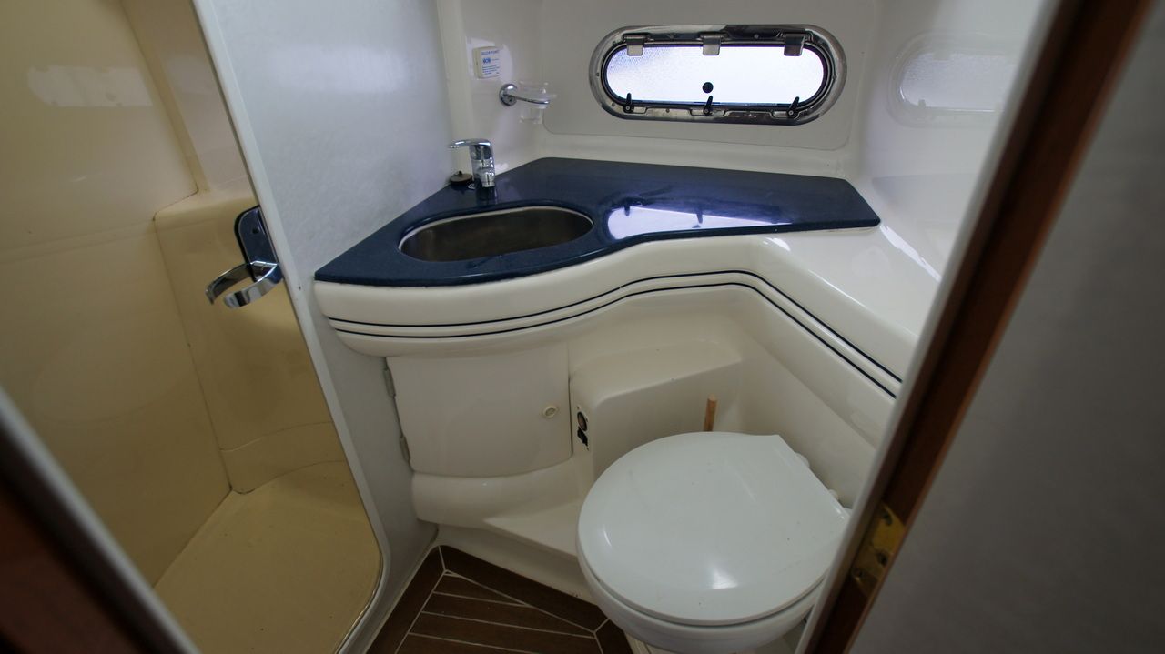 Wnętrze łazienki na jachcie Sealine F44 Flybridge z toaletą, umywalką i kabiną prysznicową.
