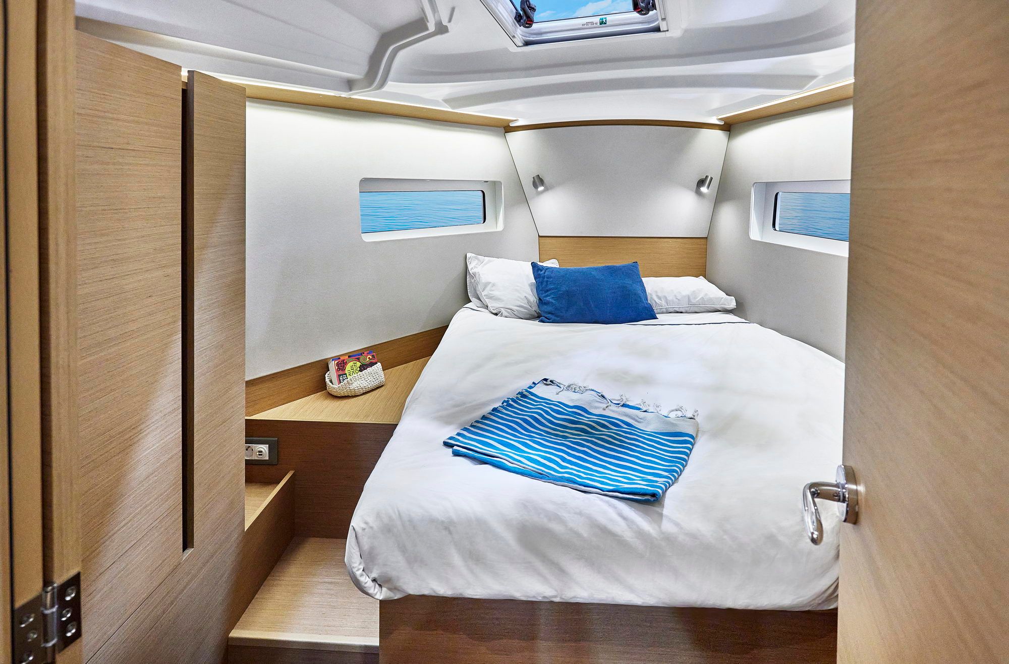Wnętrze kabiny dziobowej jachtu Jeanneau Sun Odyssey 380 z podwójnym łóżkiem i oknami.