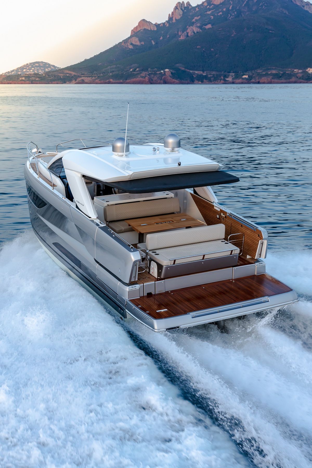 Jeanneau DB/43 IB cruising on the water, rear view. The spacious cockpit with sofas, table and swim platform is visible.
