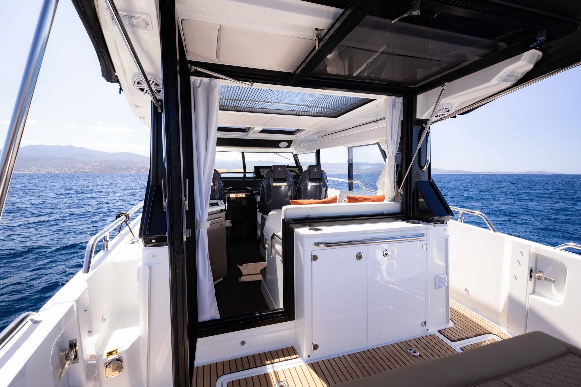 Widok na wnętrze Wellcraft 38 Explorer z kokpitem, sterówką i częścią rufową, z otwartym dachem i widokiem na morze.