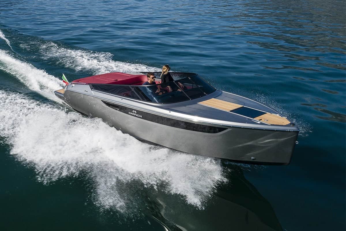 Motorówka Cranchi E26 Classic Azzurro Infinito z dwiema osobami na pokładzie, płynąca po wodzie.