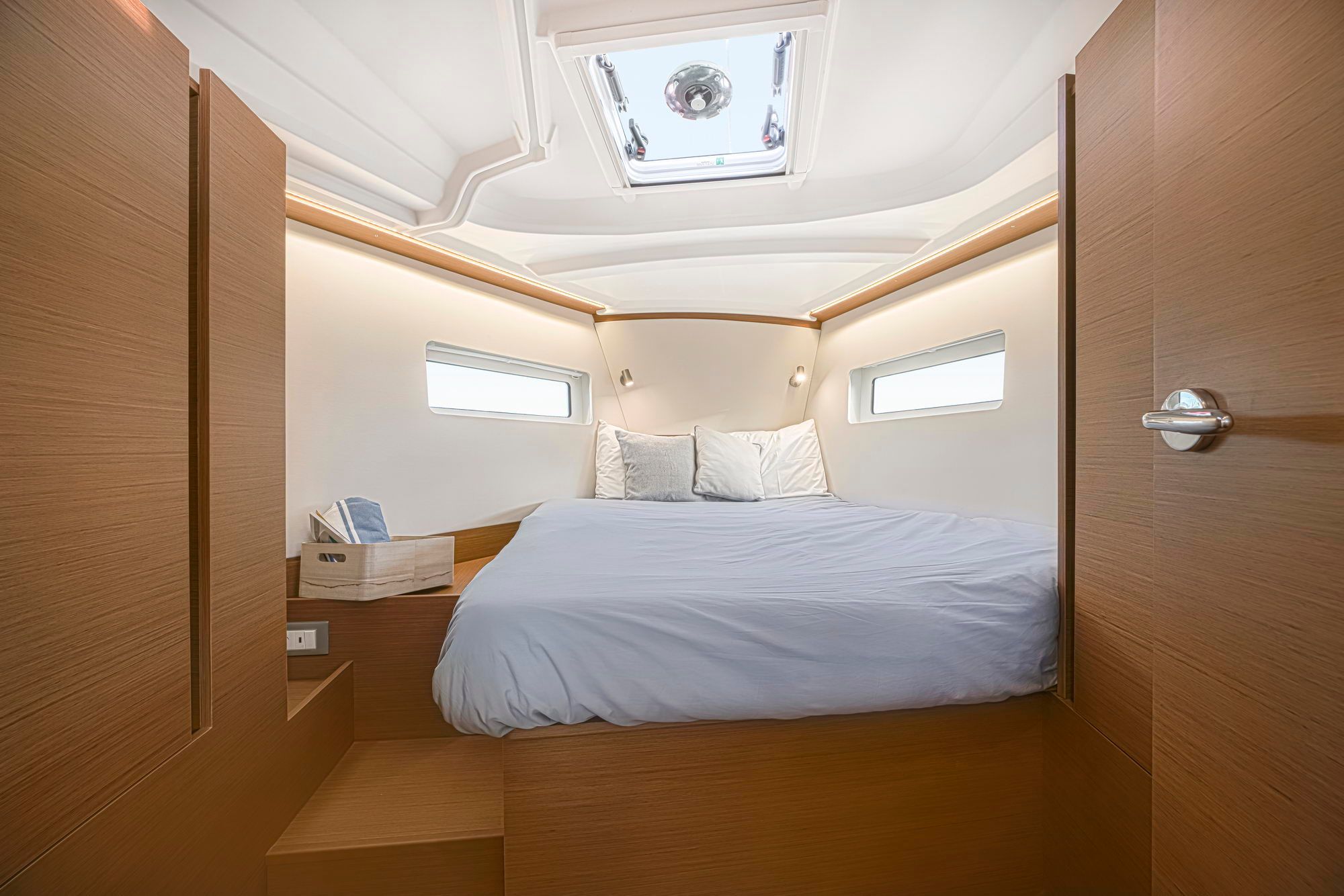 Innenraum der Bugkabine der Segelyacht Jeanneau Sun Odyssey 380 mit rechteckiger Koje, Fenstern und Luke.