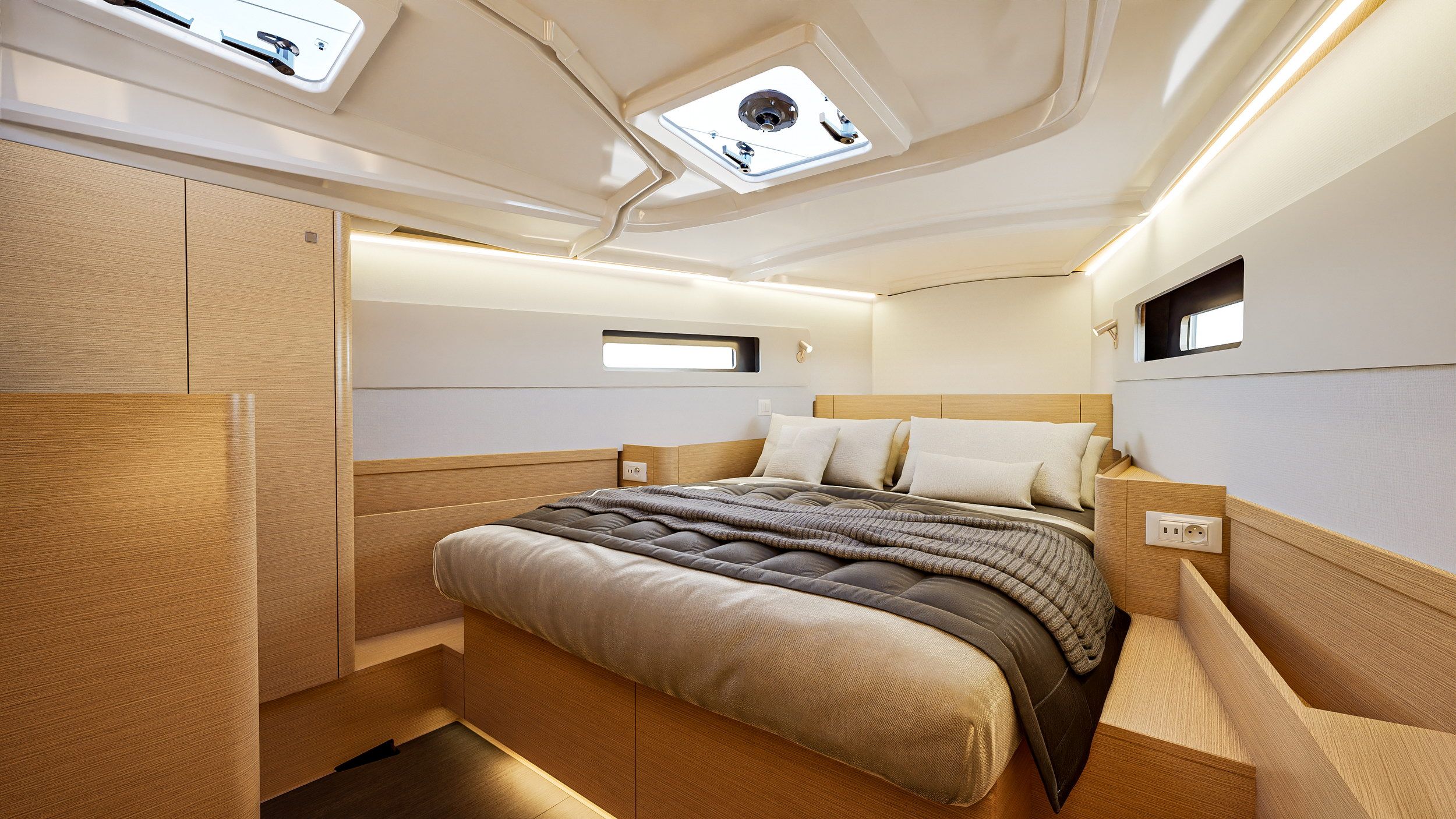Spacious bow cabin on the Jeanneau Sun Odyssey 415 with a large bed, wooden cabinets and windows. Bright interior.