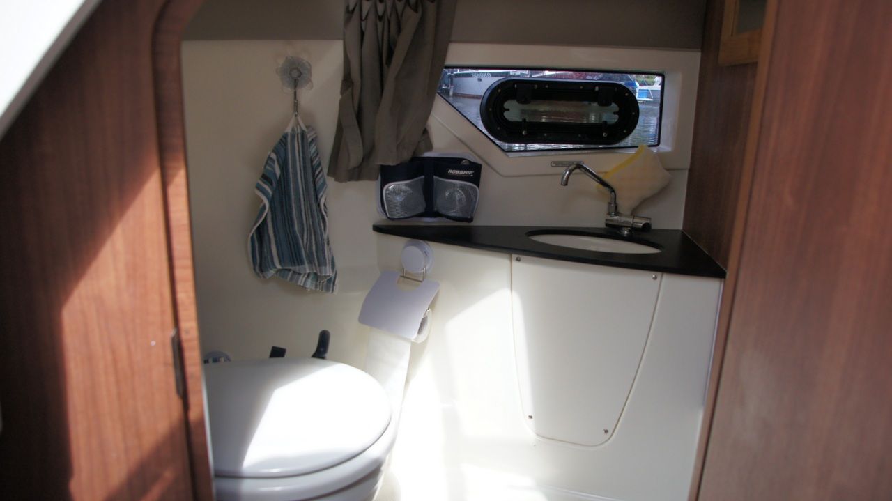 Compact marine toilet with washbasin and window in the cabin of the Uttern D77.