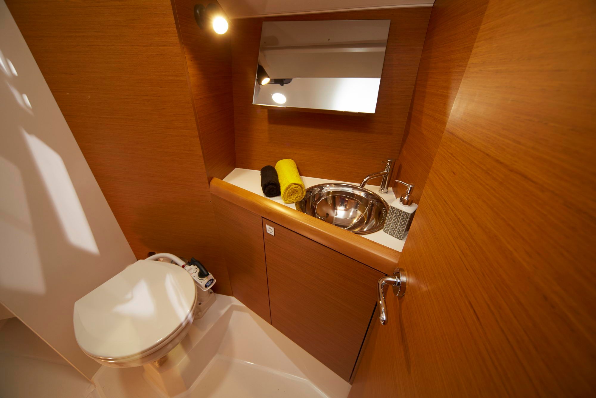 Interior of the bathroom on the Jeanneau Sun Odyssey 349 with toilet, washbasin and mirror.