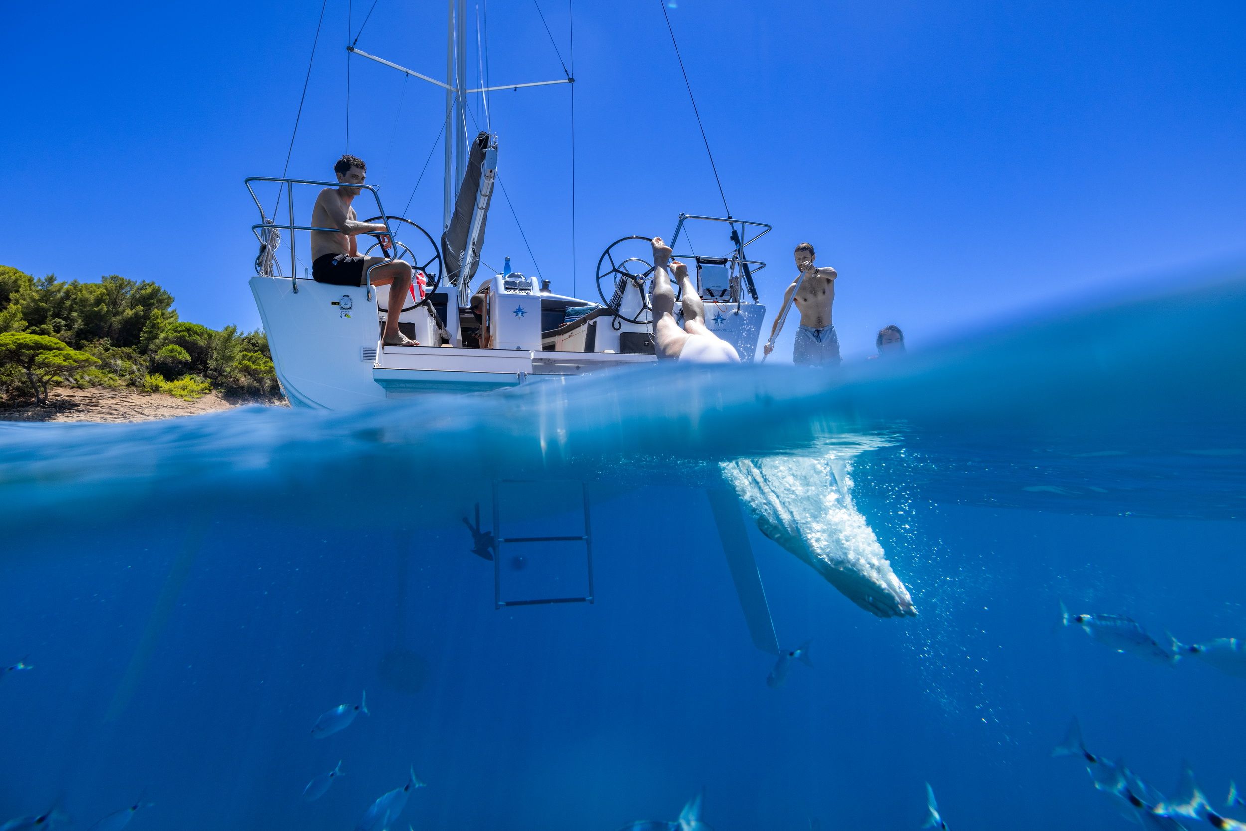 Jeanneau Sun Odyssey 415 sailing yacht with people on board and in the water, partially underwater view.