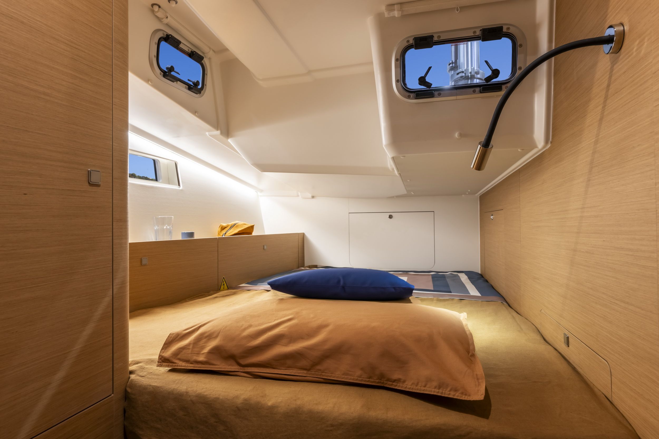 Innenraum einer Schlafkabine der Jeanneau Sun Odyssey 455 mit großem Bett, Holzverkleidung und Fenstern.