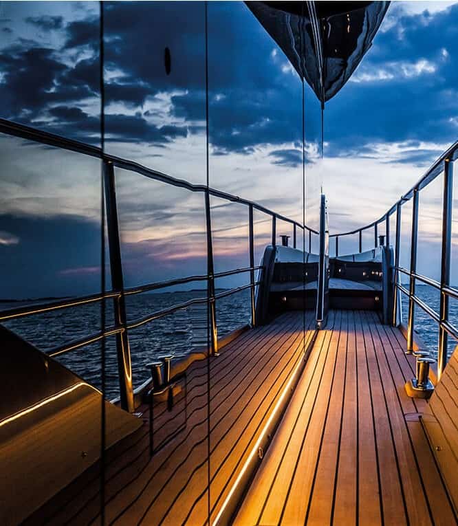 Blick auf den offenen Bugbereich der Cranchi Sessantasette 67 in der Abenddämmerung, mit Holzdeck und Beleuchtung.