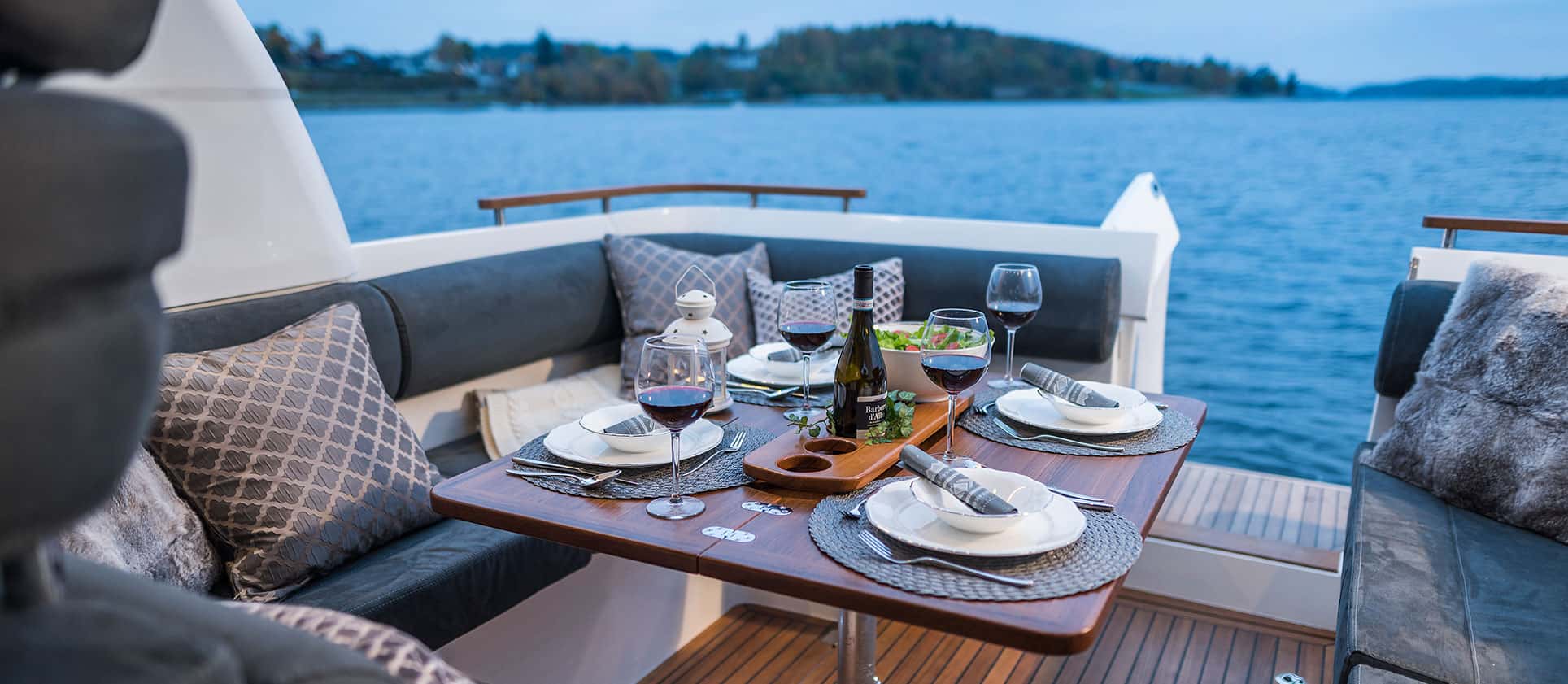 Stół w kokpicie łodzi Marex 310 Sun Cruiser zastawiony do posiłku, z widokiem na wodę.