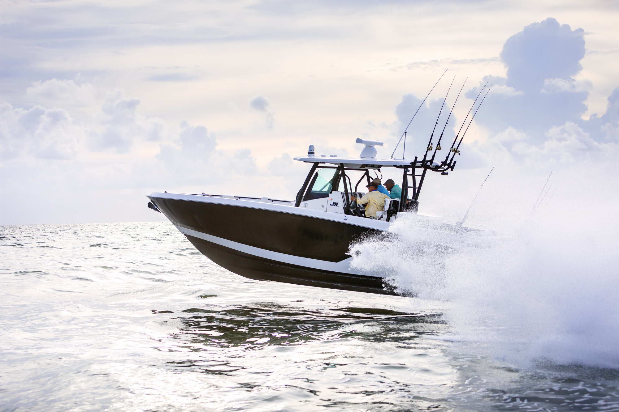 The Wellcraft Fisherman 352 underway on the water, with two people on board and fishing rods.