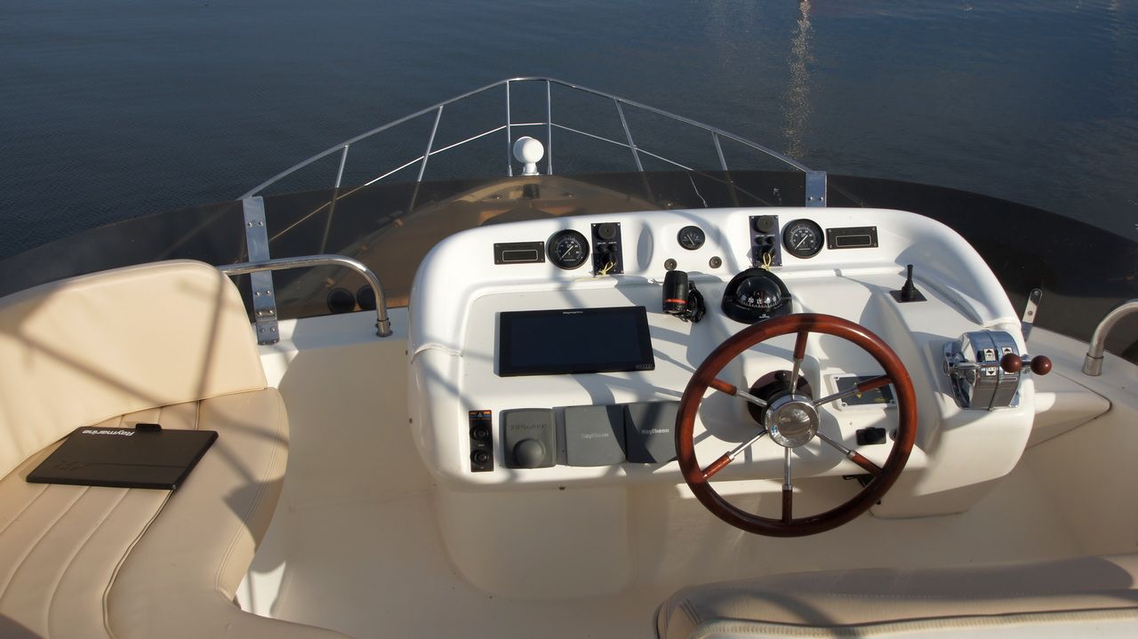 Widok na sterówkę zewnętrzną jachtu Sealine F44 Flybridge z kierownicą, manetkami i ploterem Raymarine.