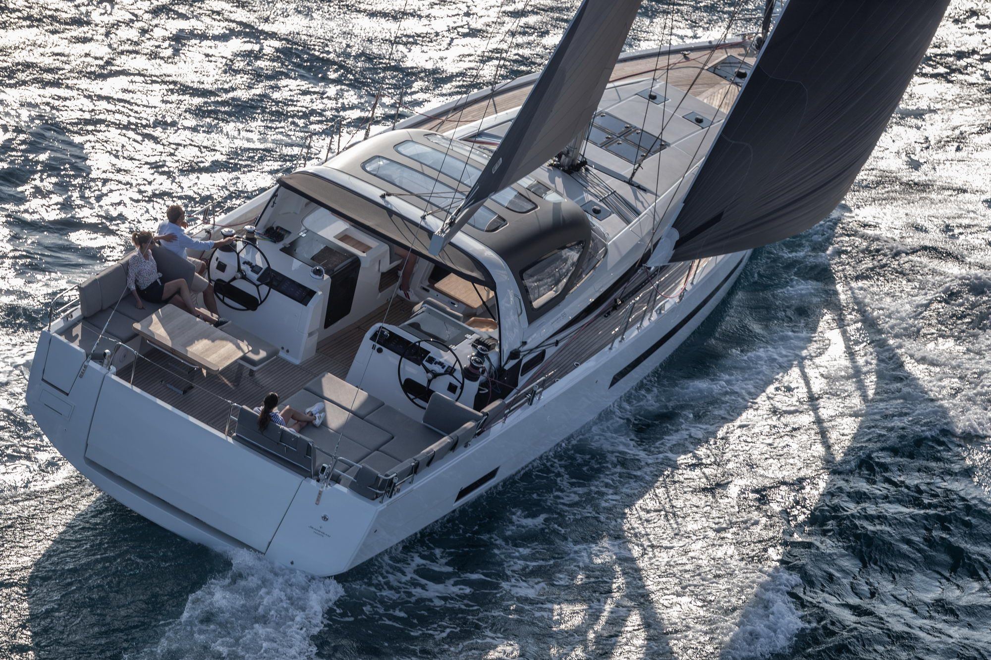Widok z góry na jacht żaglowy Jeanneau Yachts 55 płynący po morzu. Widoczny kokpit z dwoma stanowiskami sterowania, rufa i żagle.