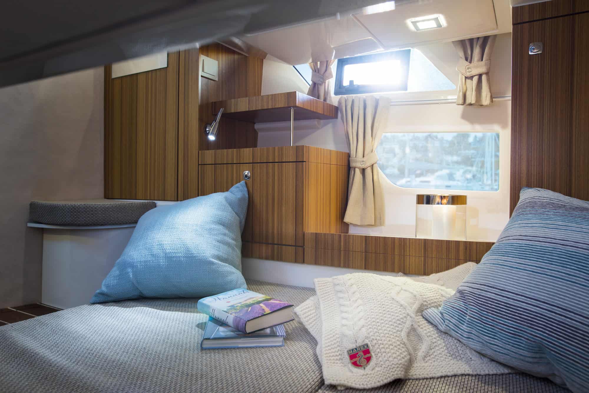 Interior of a sleeping cabin on the Marex 310 Sun Cruiser motor yacht with berth, wooden cabinets and window.