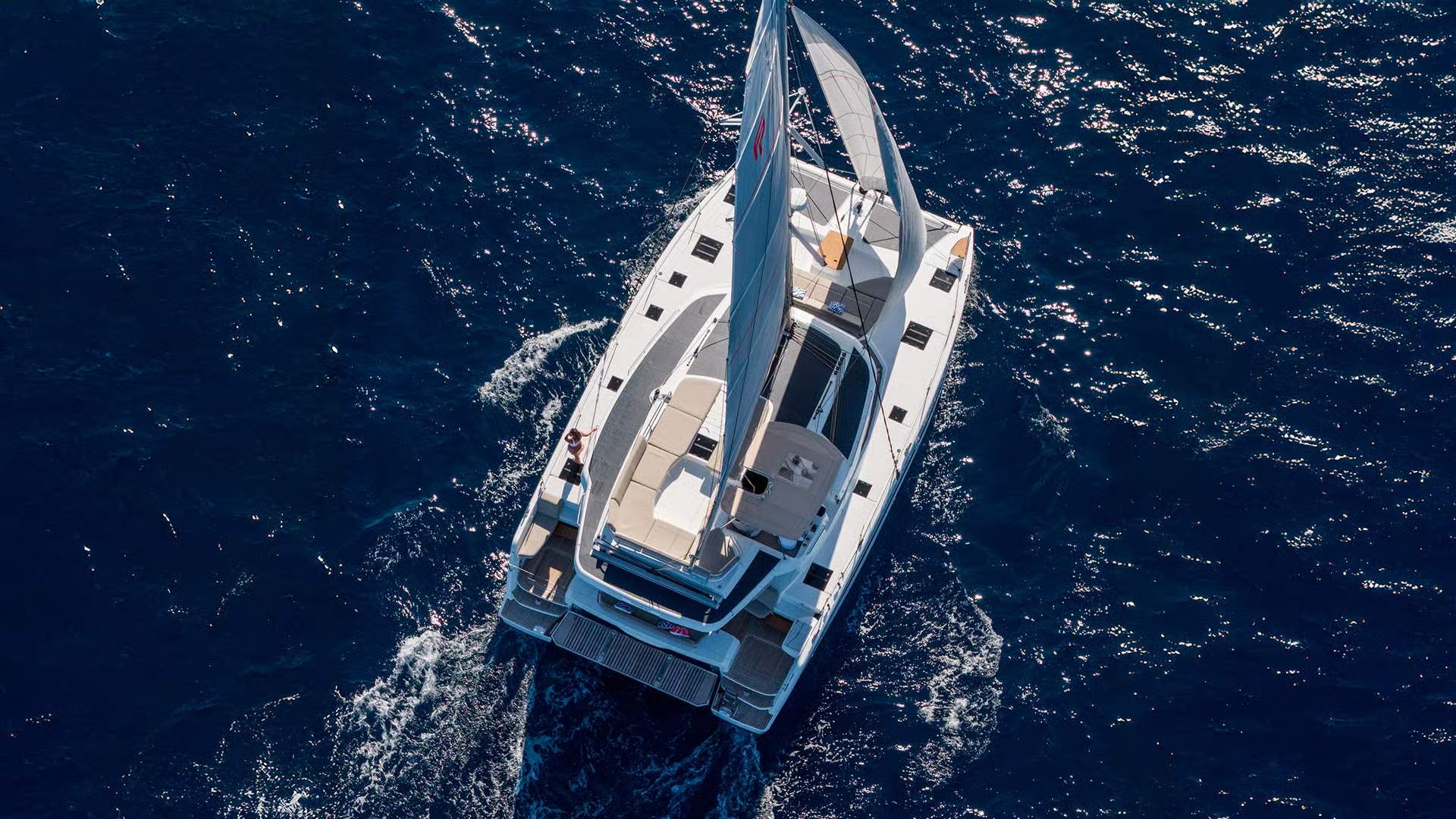 Widok z lotu ptaka na katamaran Fountaine Pajot FP44 płynący po otwartym morzu z podniesionymi żaglami.