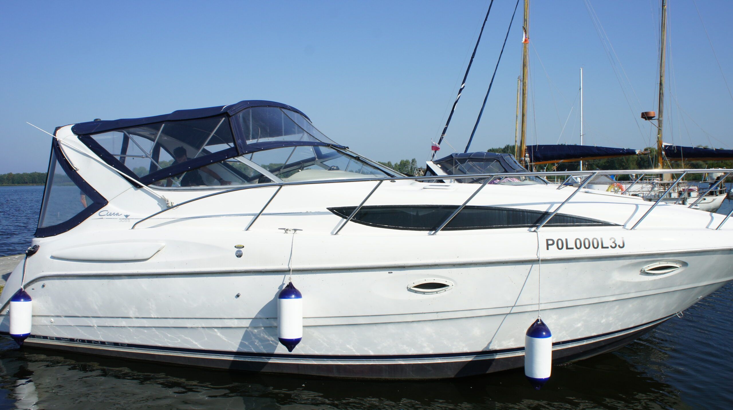 Weiße Bayliner 3055 Ciera Motoryacht mit marineblauem Bimini, im Hafen vertäut, Seitenansicht.