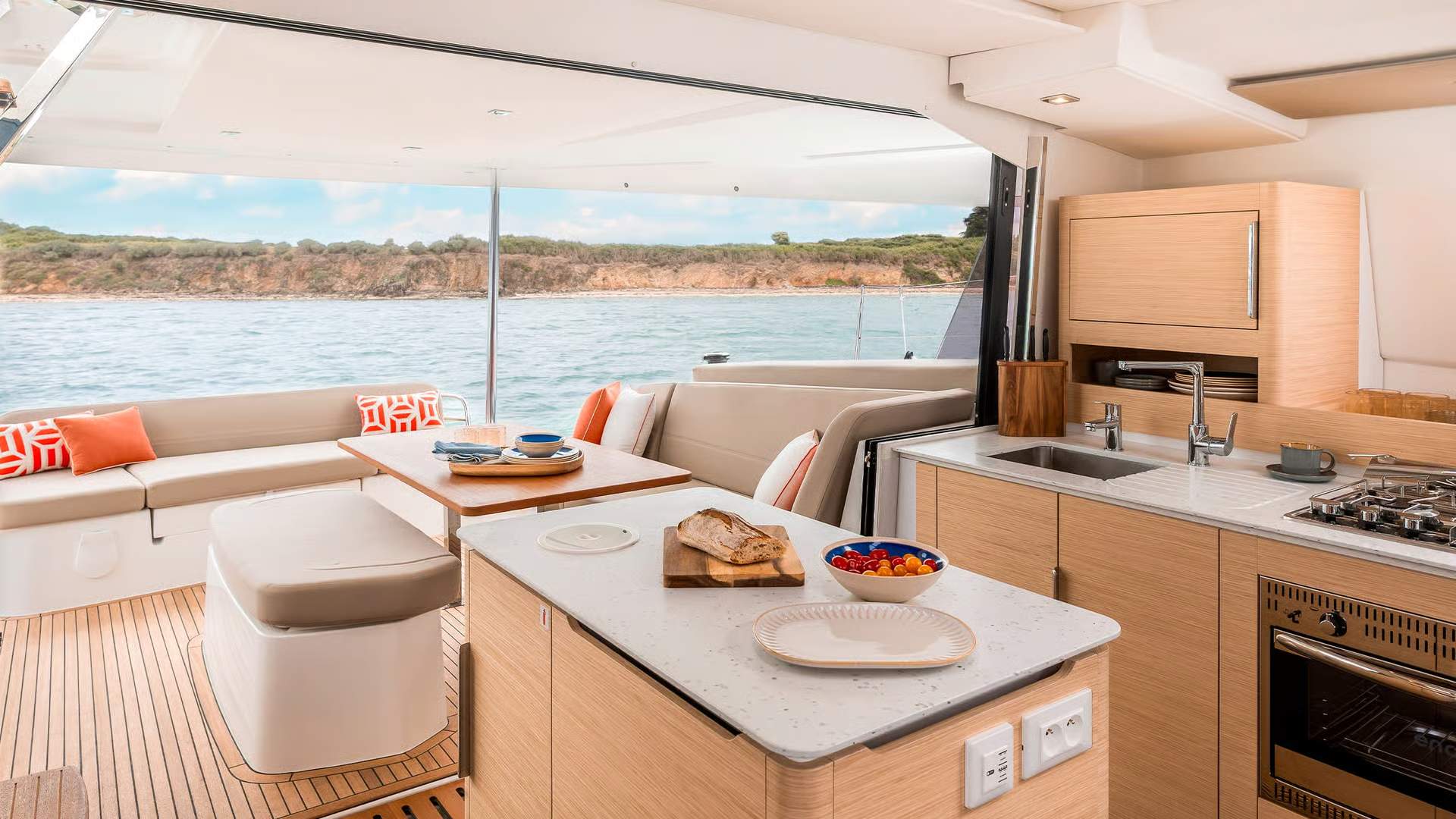 Widok na otwartą kuchnię i salon katamaranu Fountaine Pajot FP41 z widokiem na morze i wybrzeże