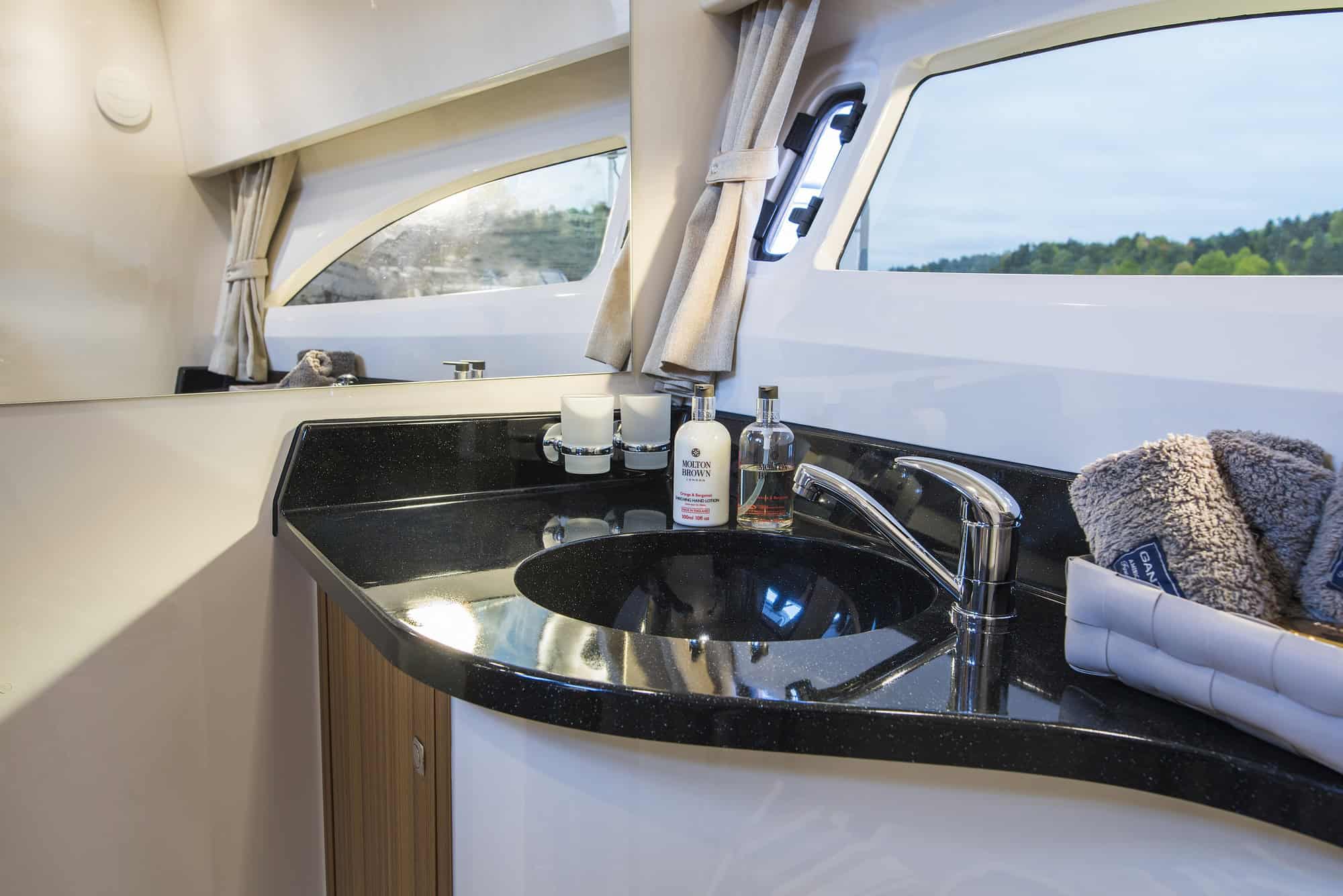 Wnętrze łazienki na jachcie Marex 310 Sun Cruiser z umywalką, lustrem i oknem bocznym.