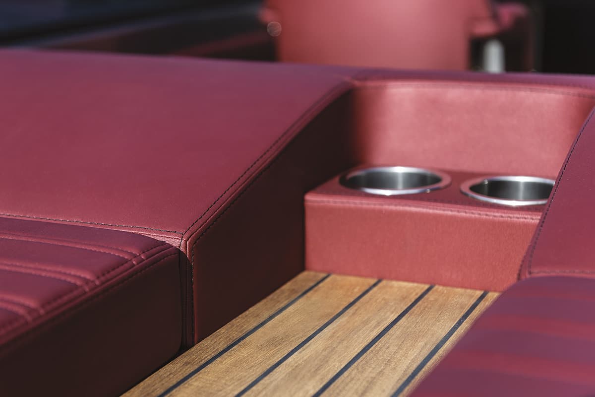 Red upholstery with two cup holders and a wooden floor in the cockpit of the Cranchi E26 Classic.
