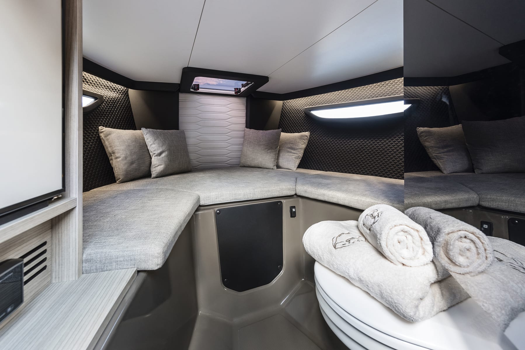 Interior of the cabin on the Cranchi E26 Classic with grey cushions, cabinet and ceiling hatch.