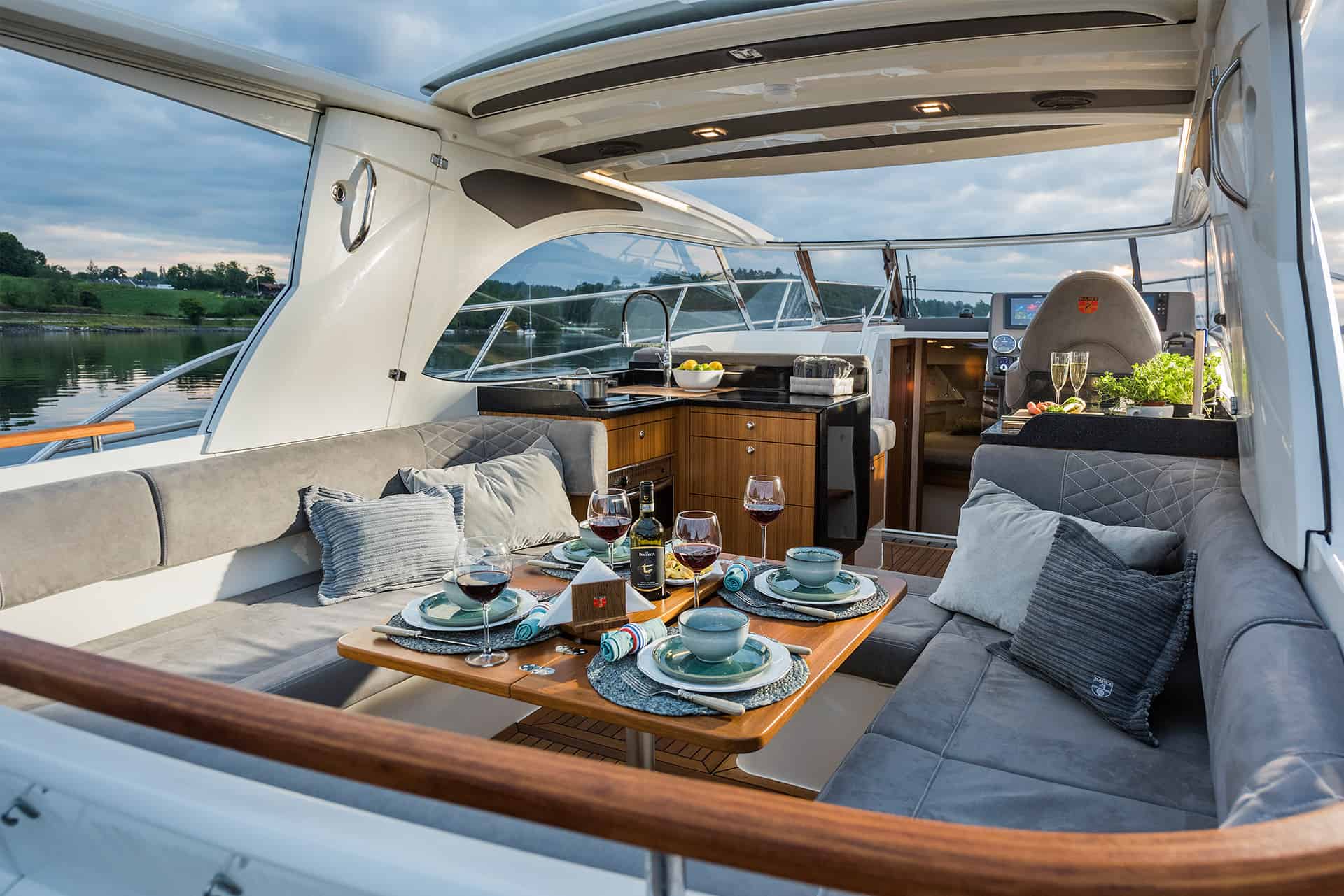 Przestronny kokpit jachtu Marex 360 Cabriolet Cruiser z zastawionym stołem jadalnym i w pełni wyposażonym kambuzem.