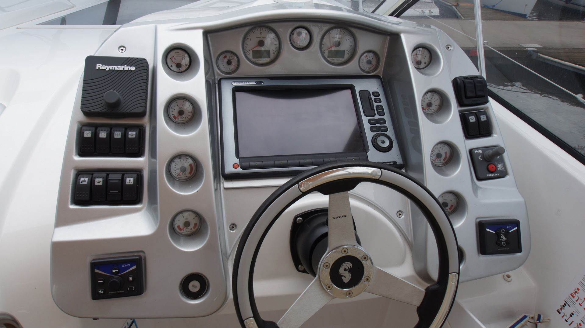 Panel sterowania jachtu motorowego Beneteau Monte Carlo 37 Open z kierownicą, ploterem, autopilotem i wskaźnikami.