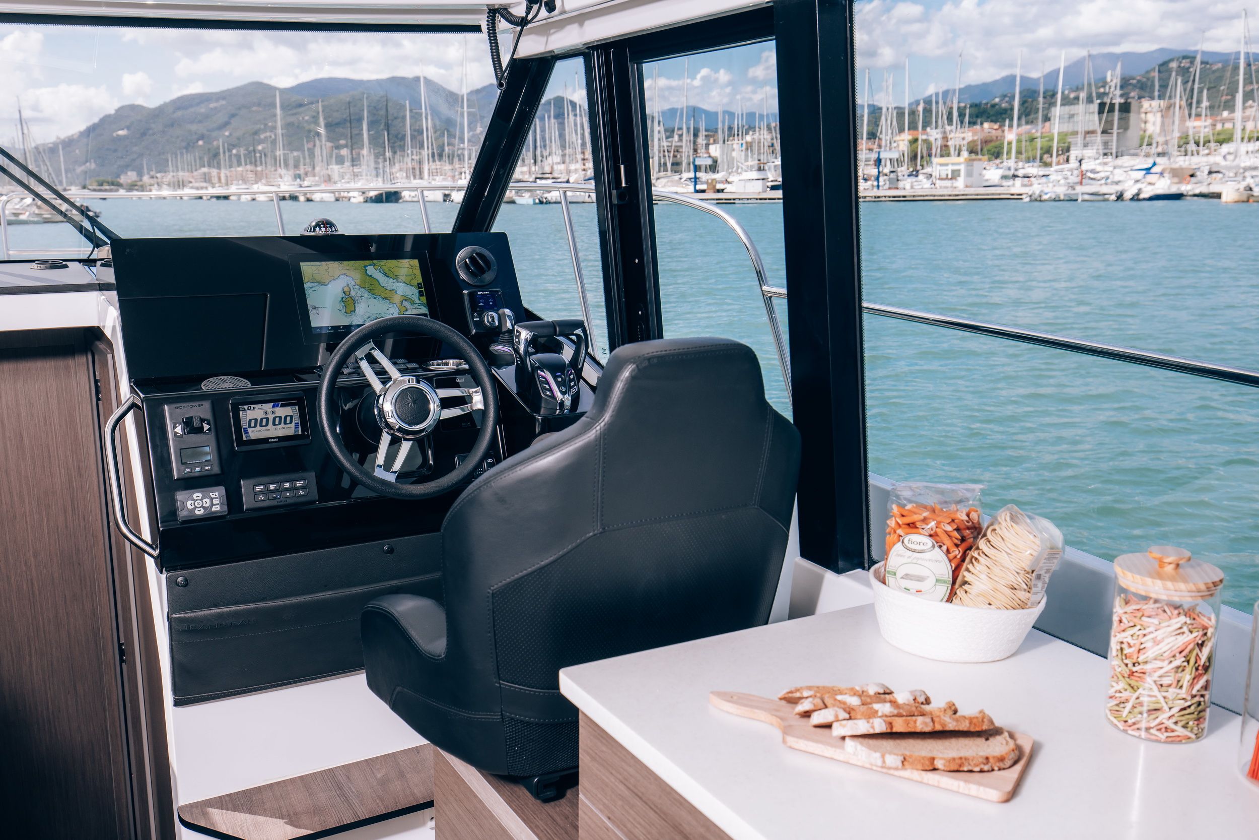 Interior of the Jeanneau Merry Fisher 1095 Fly Serie2 with a view of the helm station, navigation display and the marina.