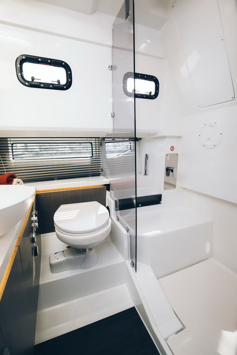 The bathroom interior on the Wellcraft 38 Explorer, with a toilet, washbasin and separate shower. Windows and white finishes are visible.