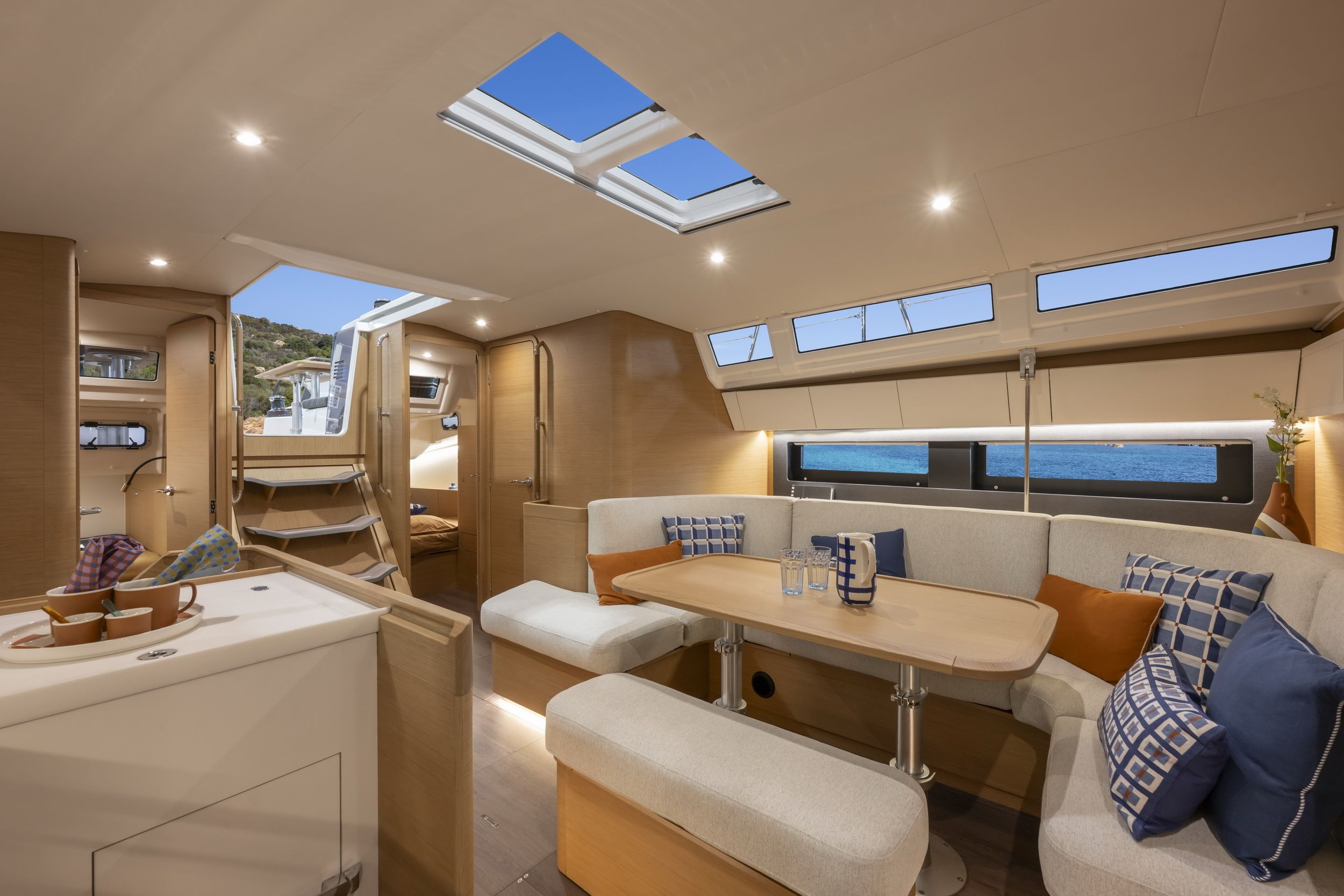 Przestronny salon jachtu Jeanneau Sun Odyssey 455 z dużym stołem, wygodnymi kanapami i widokiem na morze przez okna.