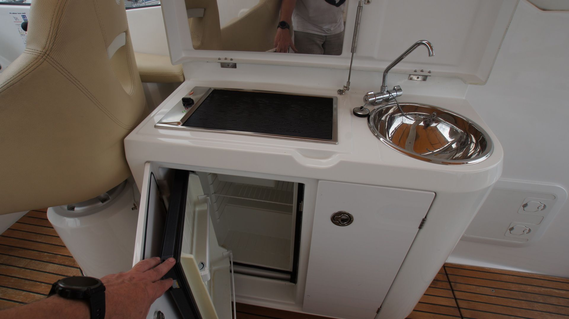 Grill, Spüle und Kühlschrank im Cockpit der Beneteau Monte Carlo 37 Open. Der geöffnete Kühlschrank ist zu sehen.