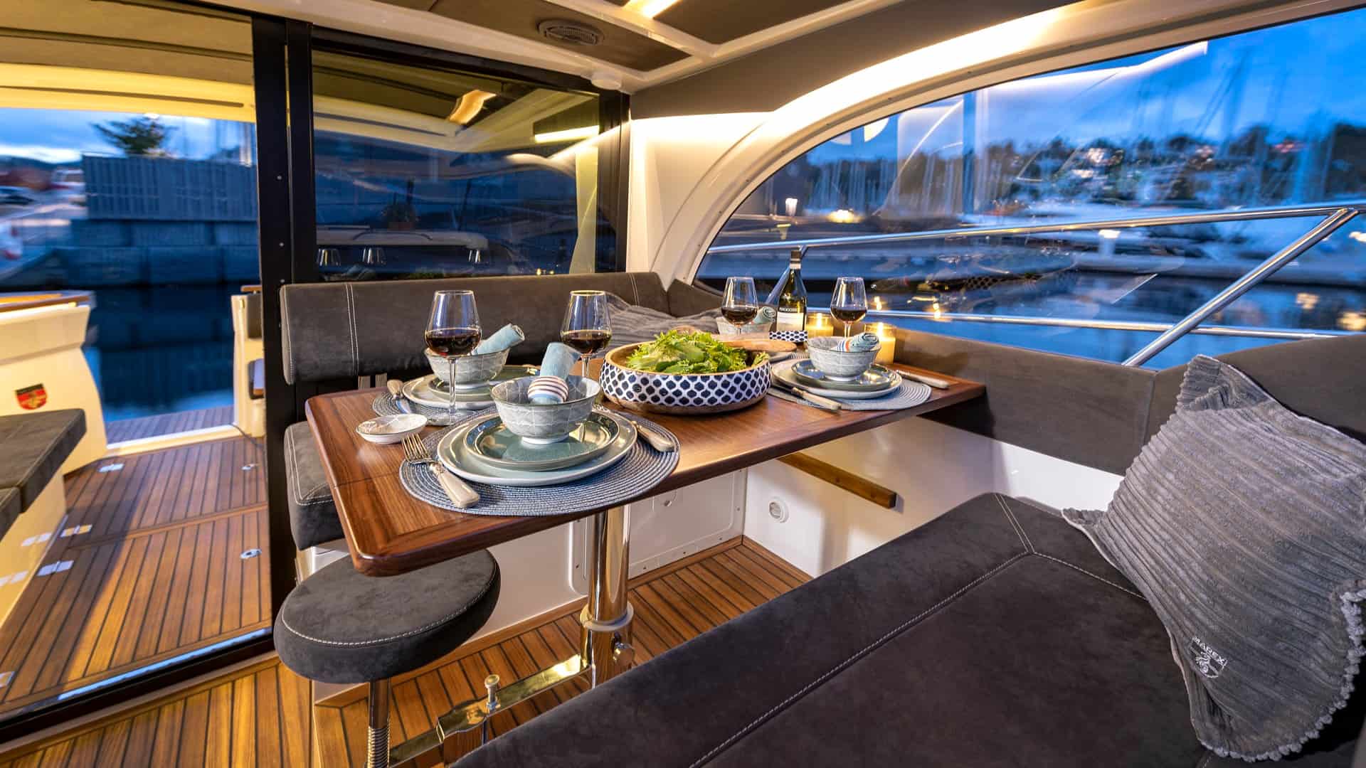 Interior of the Marex Scandinavia 330 with a set table and a view of the marina.