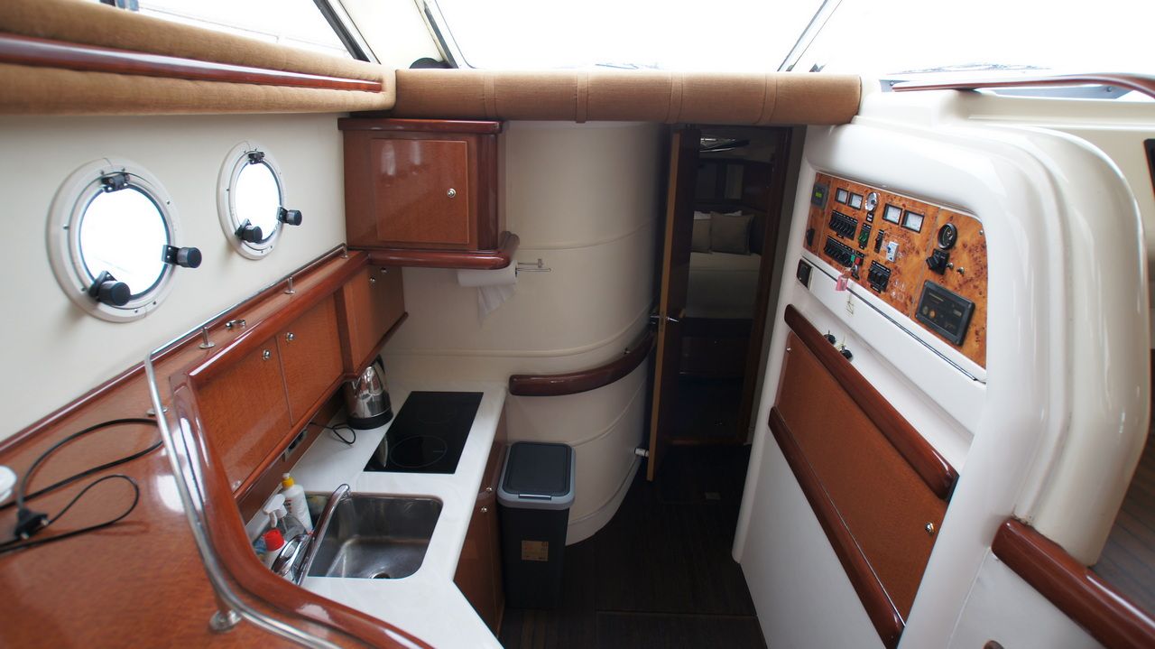 Innenraum der Sealine F44 Flybridge mit Kombüse, sichtbarer Spüle, Kochfeld und Bedienpanelen.