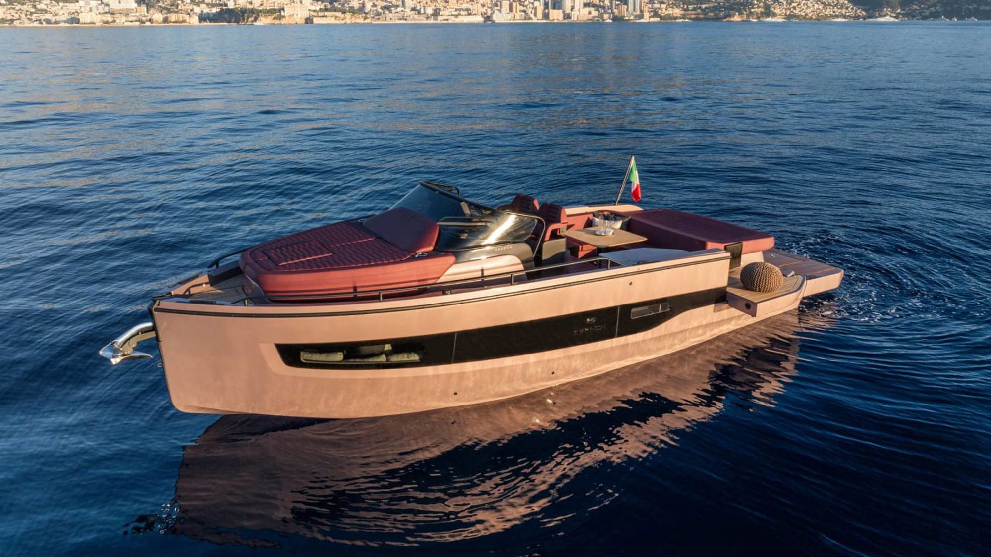 Cranchi A32 Luxury Tender na otwartej wodzie z widokiem na miasto w tle, ukazujący pokład i rufę.